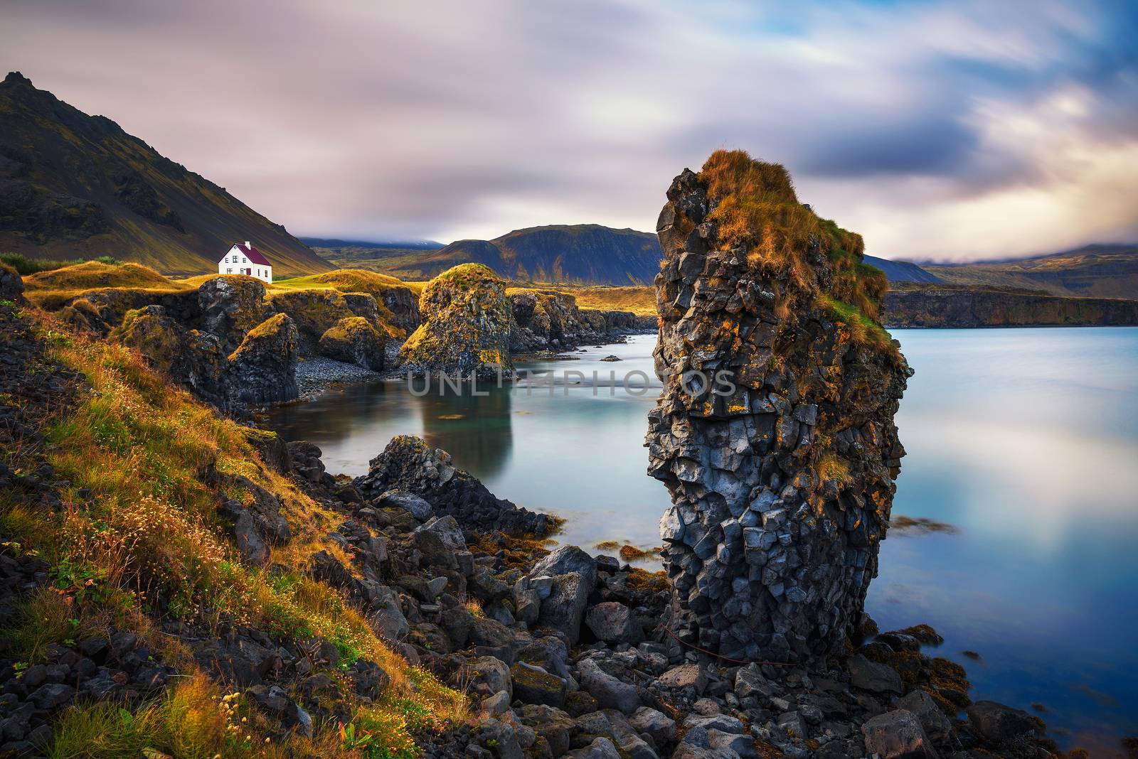 Sea shore in Iceland with cliffs and a small house in the village of Arnarstapi by nickfox