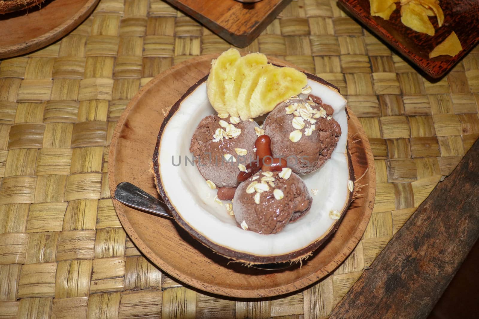 Chocolate ice cream served in fresh coconut with flesh. Sweet dessert with cocoa cookies, , banana slices and pieces of cinnamon. Delicious delicious dessert suitable as refreshment on summerer days.