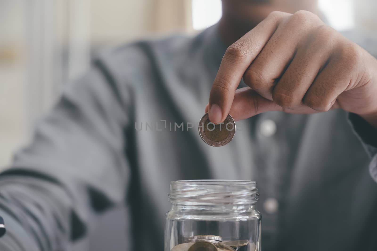 Closeup male hand holding coins putting in glass. Saving money for finance accounting concept.