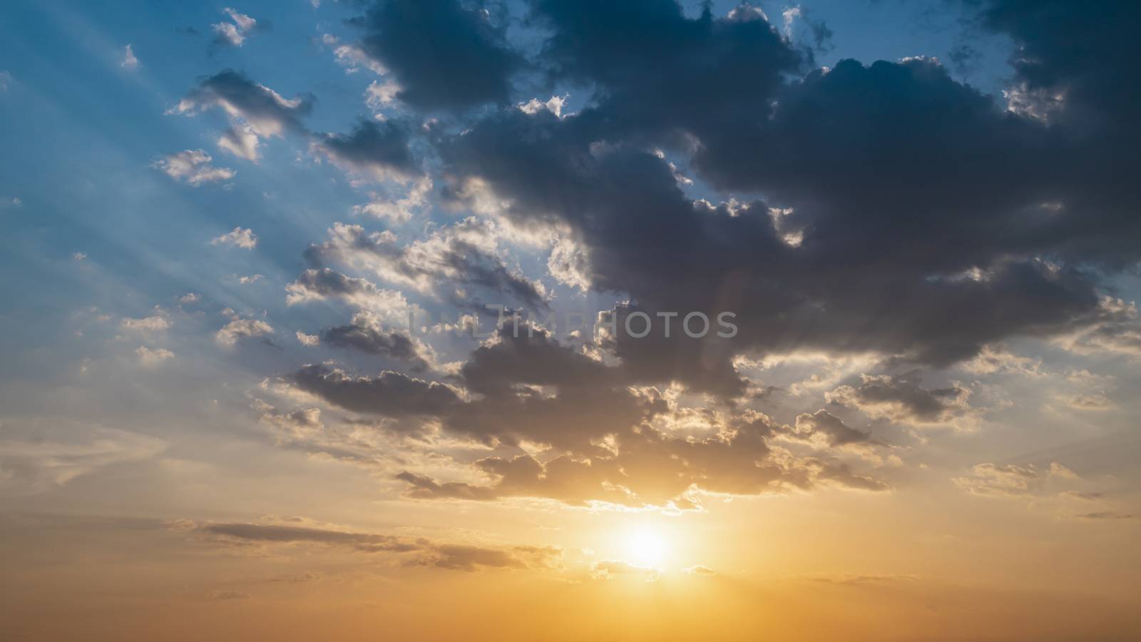 Blue and orange sunset sky with rays of sun. Natural landscape for background, early morning sky scene