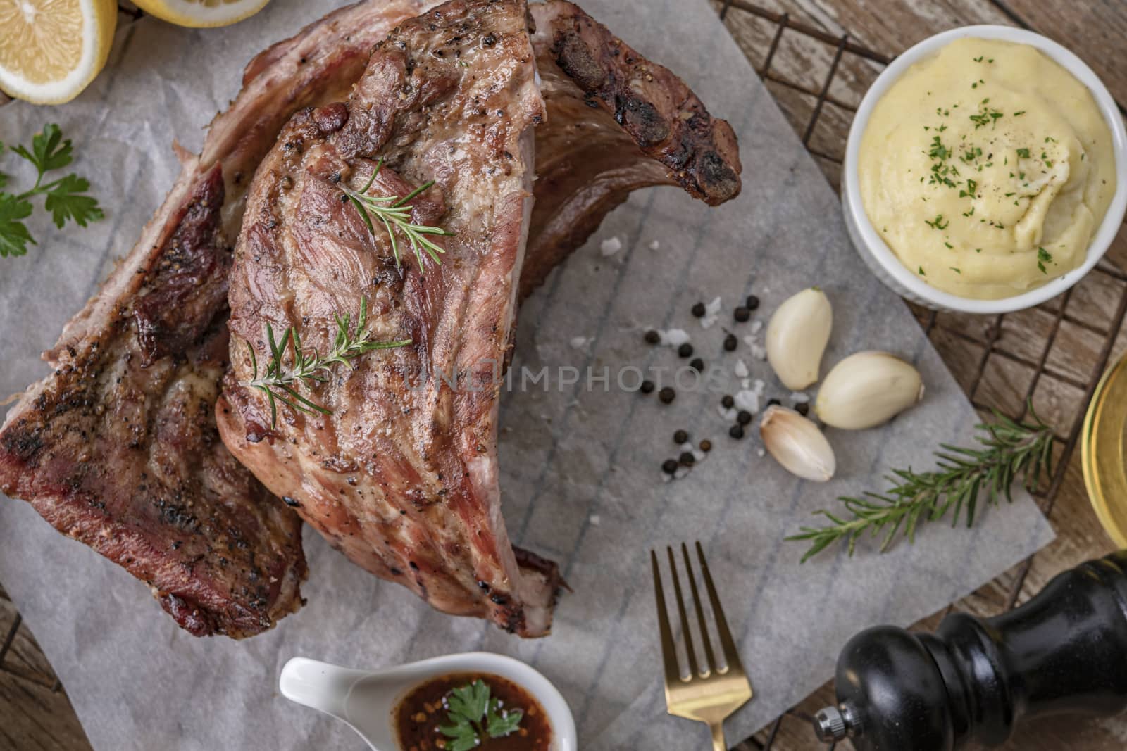 Grilled pork ribs with mashed potatoes placed on a wooden table.