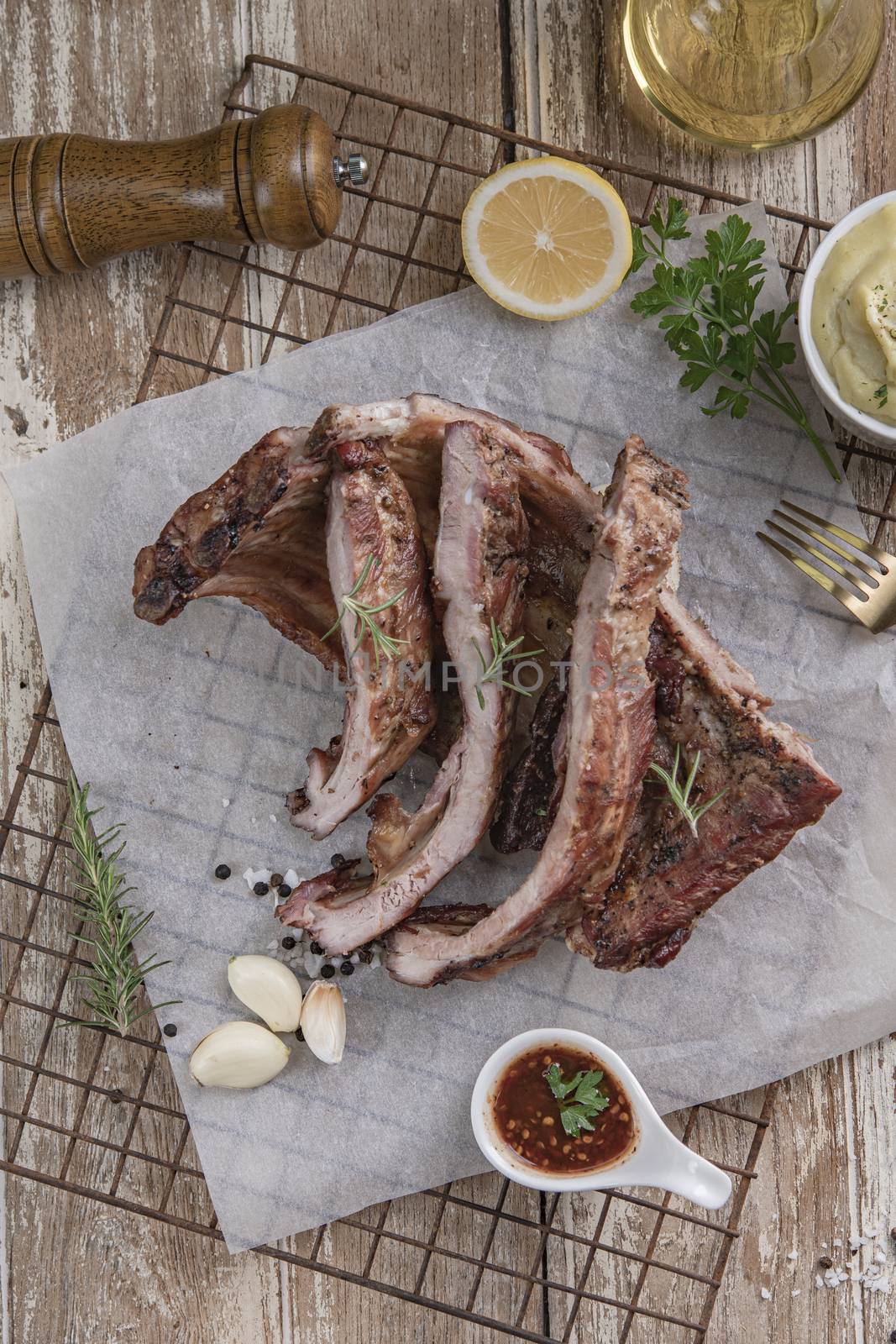 Grilled pork ribs with mashed potatoes placed on a wooden table.