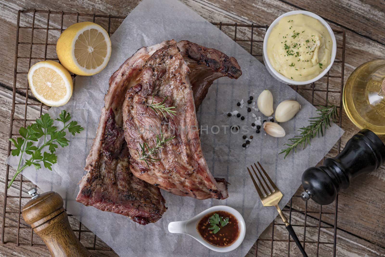 Grilled pork ribs with mashed potatoes placed on a wooden table.