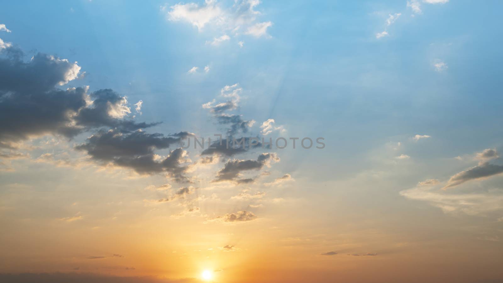 Blue and orange sunset sky with rays of sun. Natural landscape for background, early morning sky scene