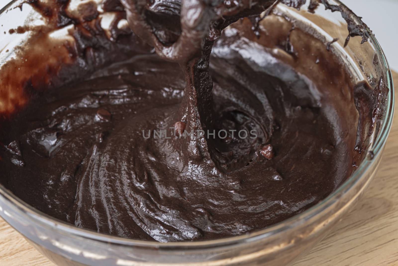 Melted chocolate swirl background, Baker or chocolatier preparing chocolate bonbons whisking the melted chocolate with a whisk dripping below.