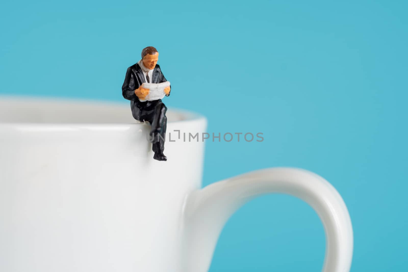 business miniature figures sitting and read a book, read newspaper, waiting, talking and relax on white cup of hot coffee.