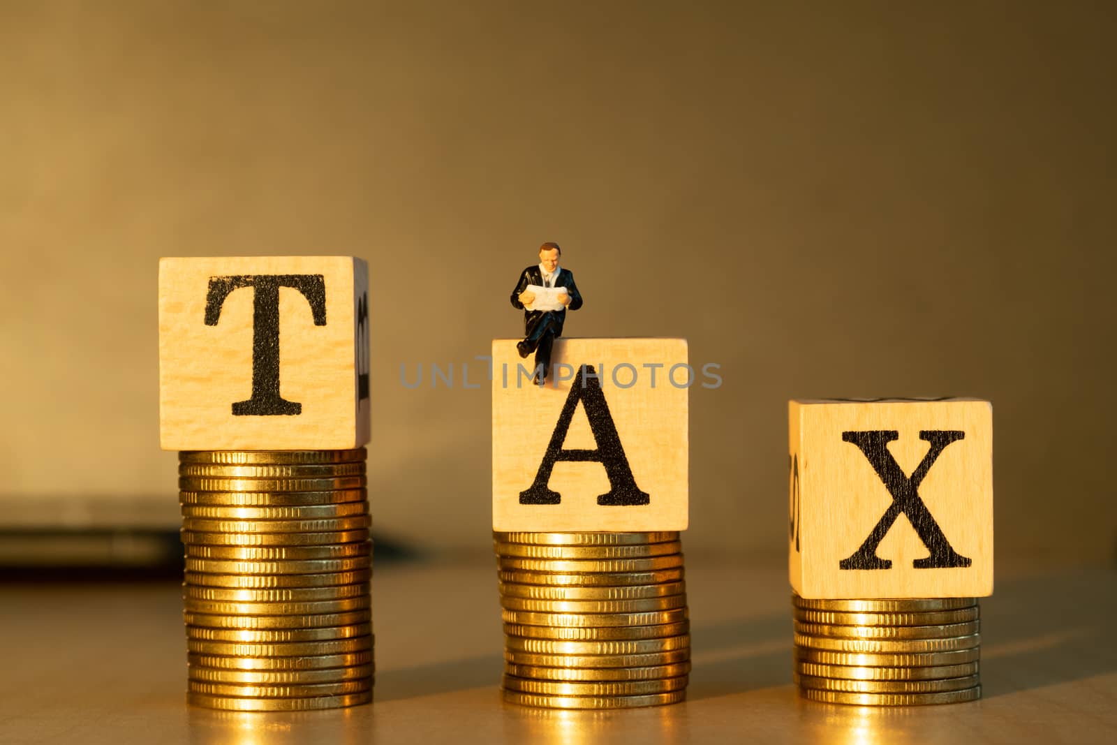 Tax Concept. Miniature businessman and gold coins. by Toefotostock