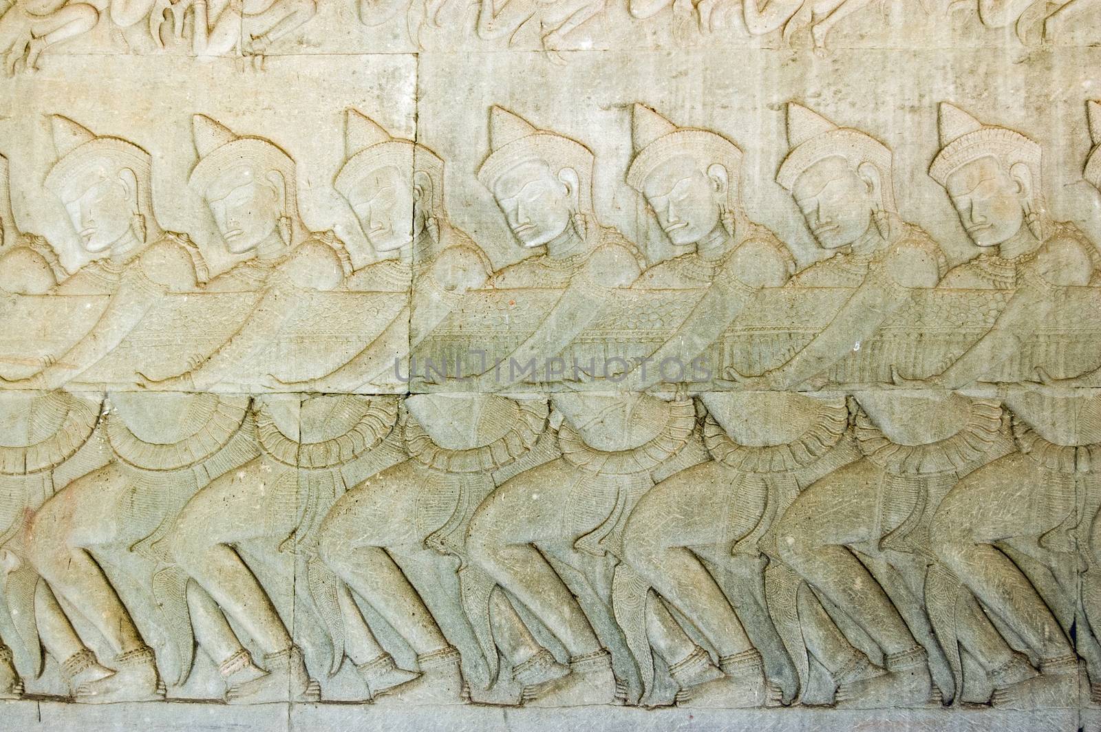 Ancient Khmer bas relief carving showing a row of Hindu gods, devas, pulling on the snake Vasuki. Legend of the churning of the Ocean of Milk, Angkor Wat temple, Cambodia.