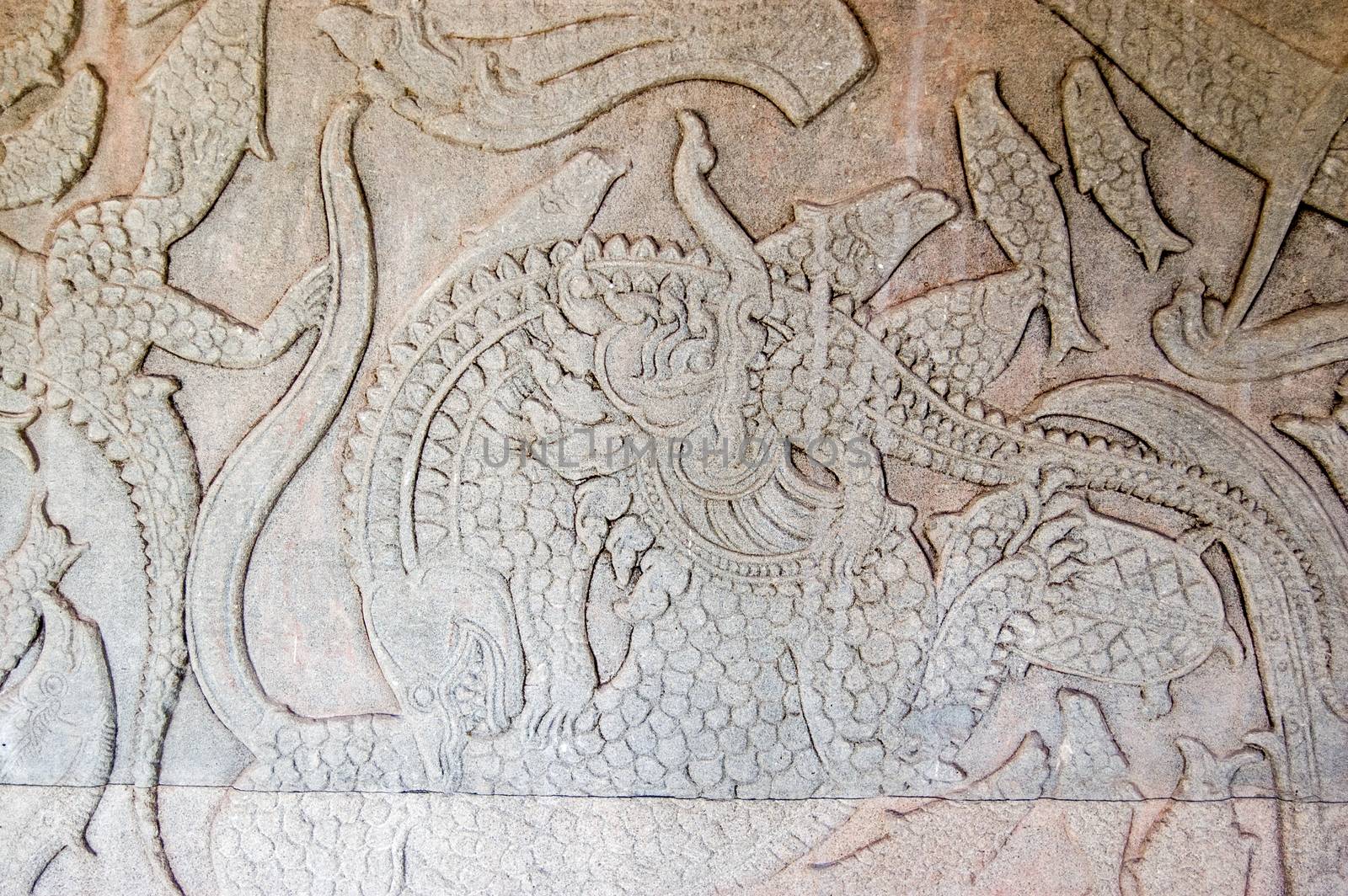 Ancient Kymer carving of the creation of the world with god fighting demons A Chinese Lion is fighting a crocodile. Churning of the Ocean of Milk gallery, Angkor Wat, Siem Reap, Cambodia.