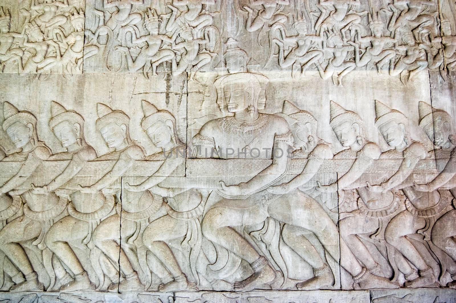 Ancient Khmer bas relief carving showing a row of Hindu gods, devas, pulling on the snake Vasuki. Legend of the churning of the Ocean of Milk, Angkor Wat temple, Cambodia.