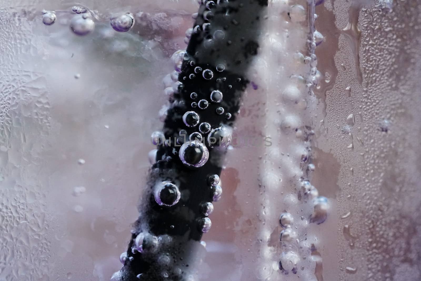 Close up glass of cool water with straw and bubbles.