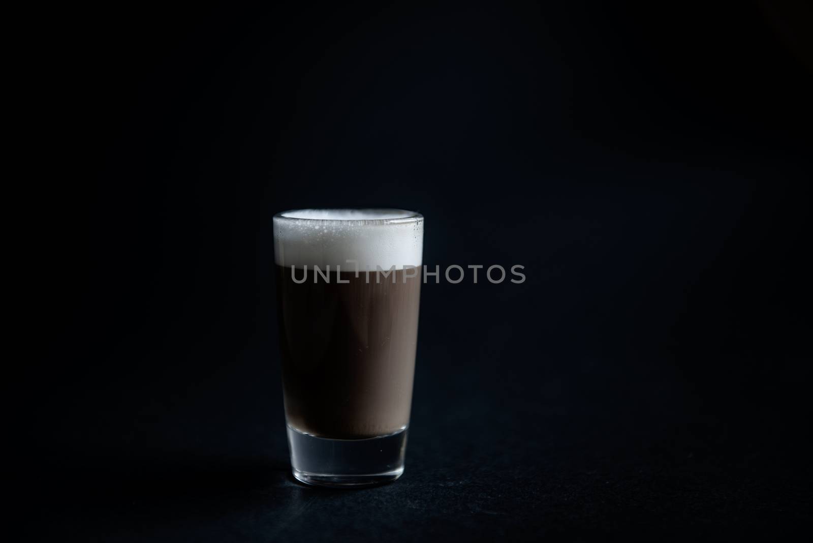 mini cup of cappuccino in a glass cup on black background by marynkin
