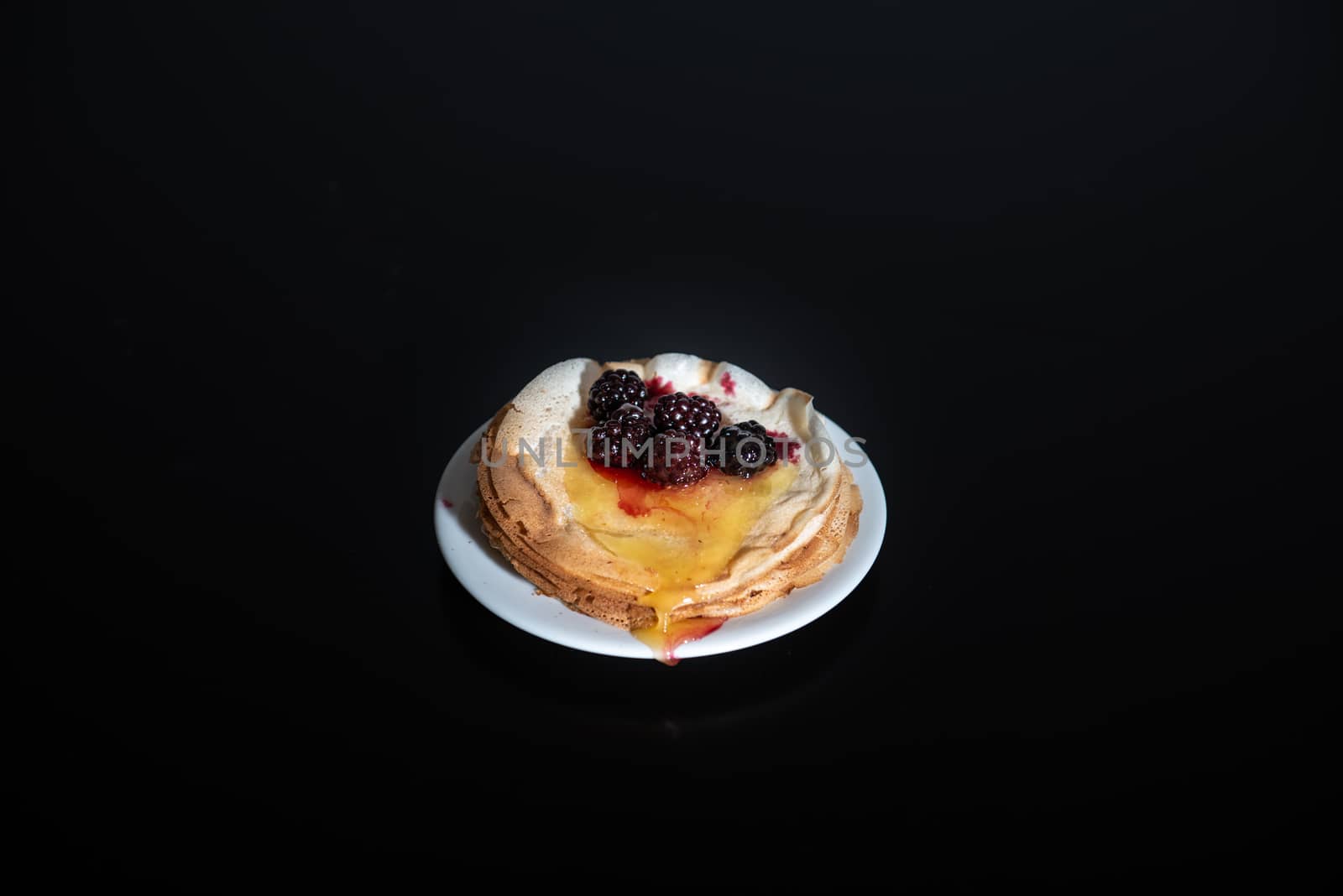 Stack of thin pancakes poured with honey and decorated with fresh blueberries side view with selective focus and dark background with copy space by marynkin