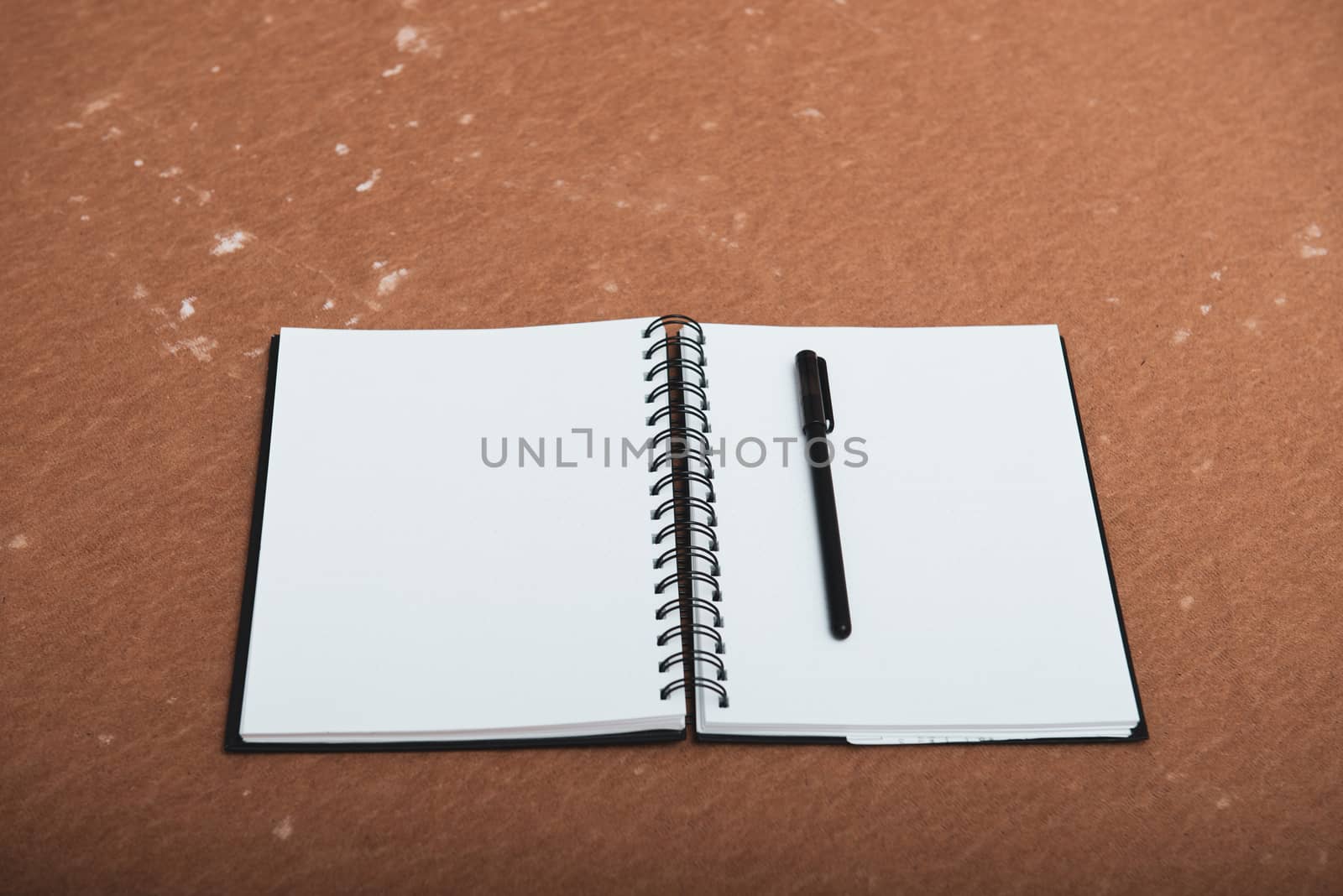 open spiral notebook to point with a pen on a brown background