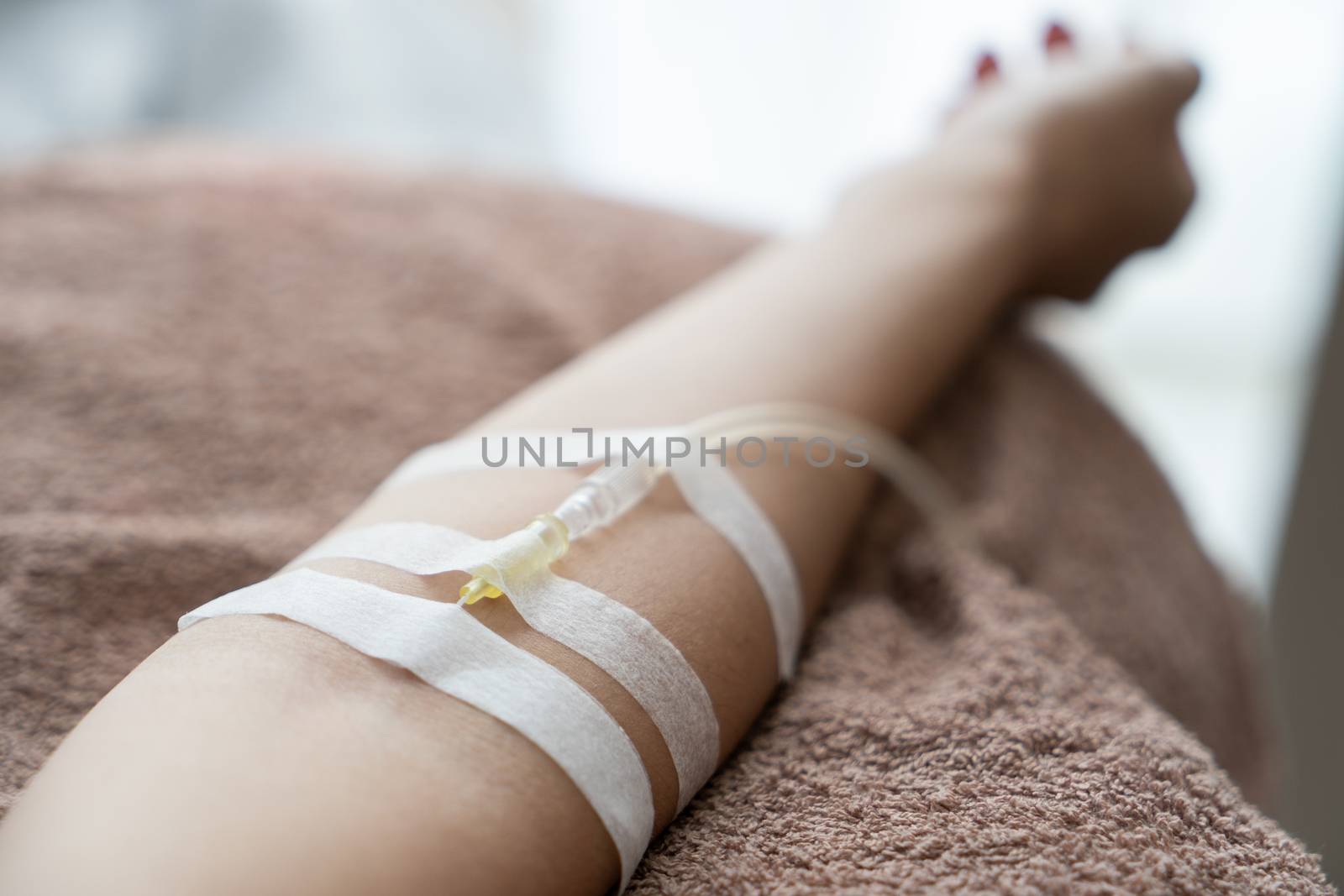 Patient with intravenous drip receiving saline solution. Injecting needle in to the arm.