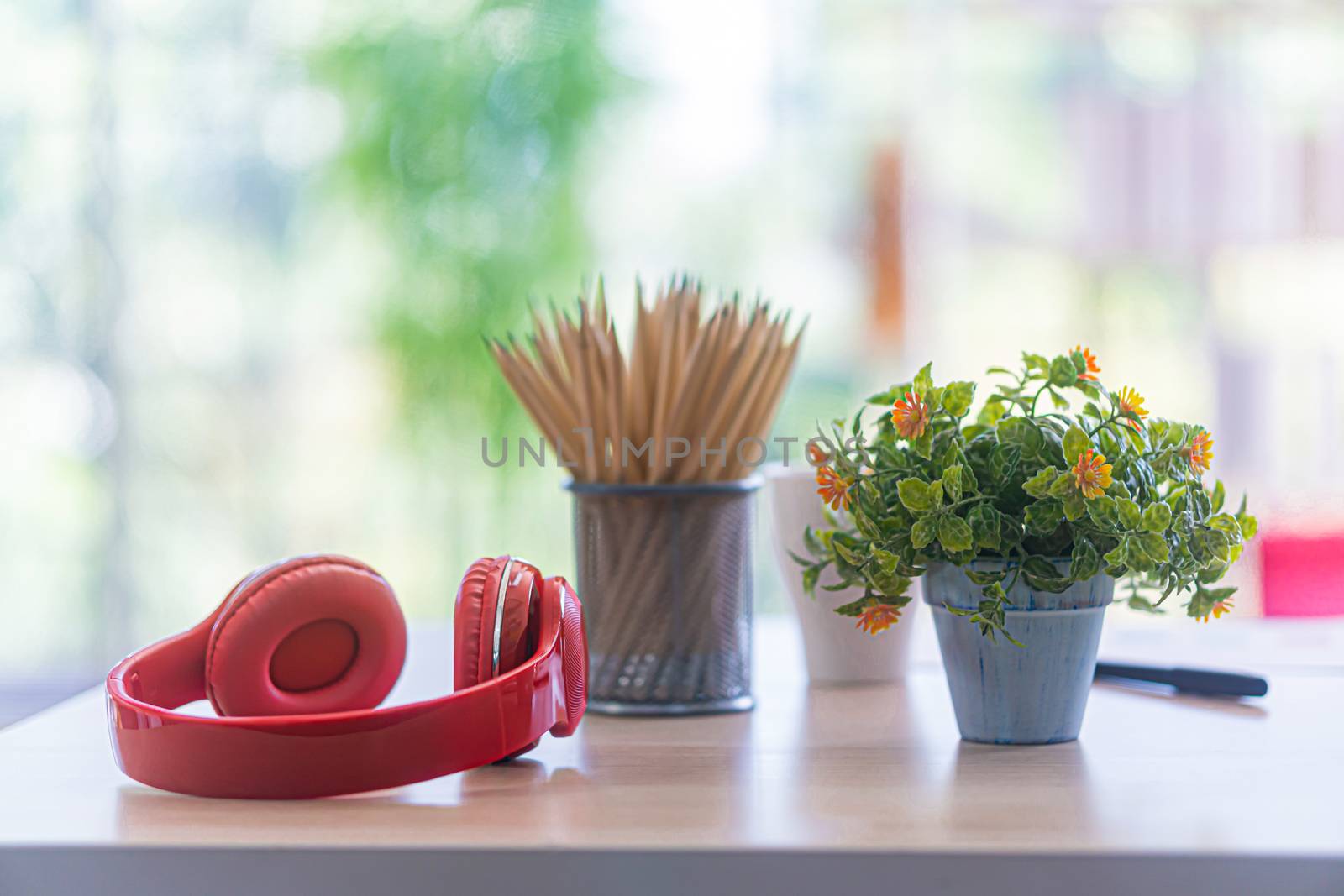 the red head phone and pencil case on white table by sandyman