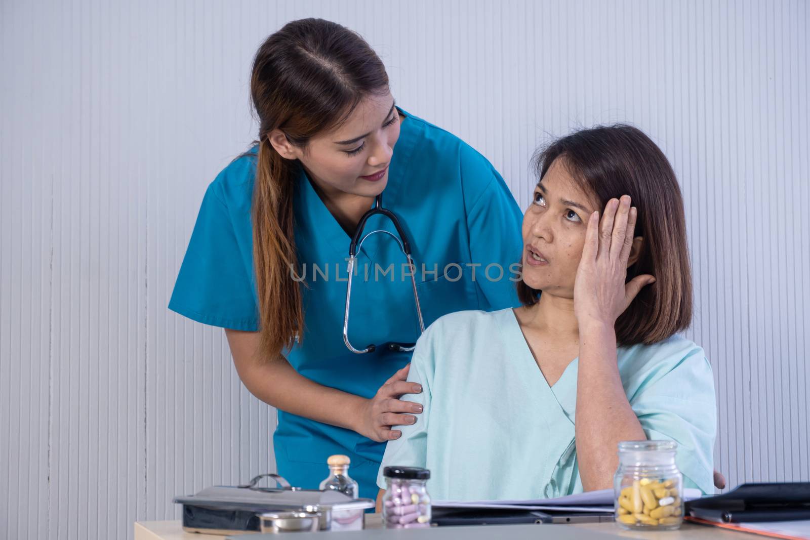 Asian Female Patient Being Reassured By Woman Doctor In Hospital Room