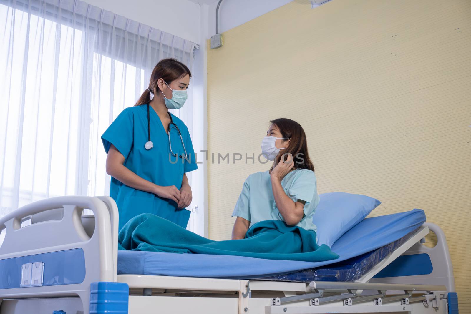 Asian Female Patient Being Reassured By Woman Doctor In Hospital Room