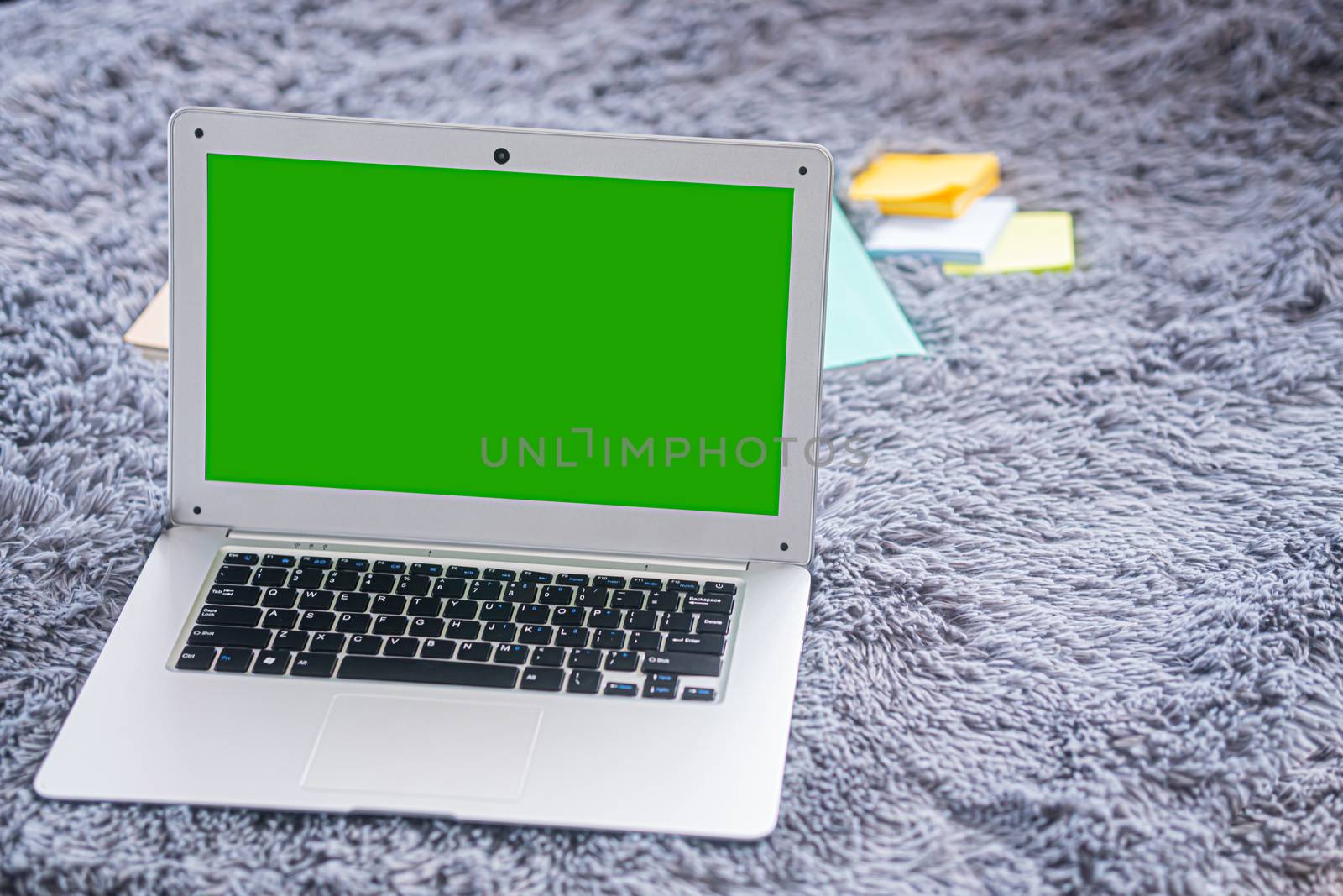 lap top computer with green screen on gray carpet  by sandyman