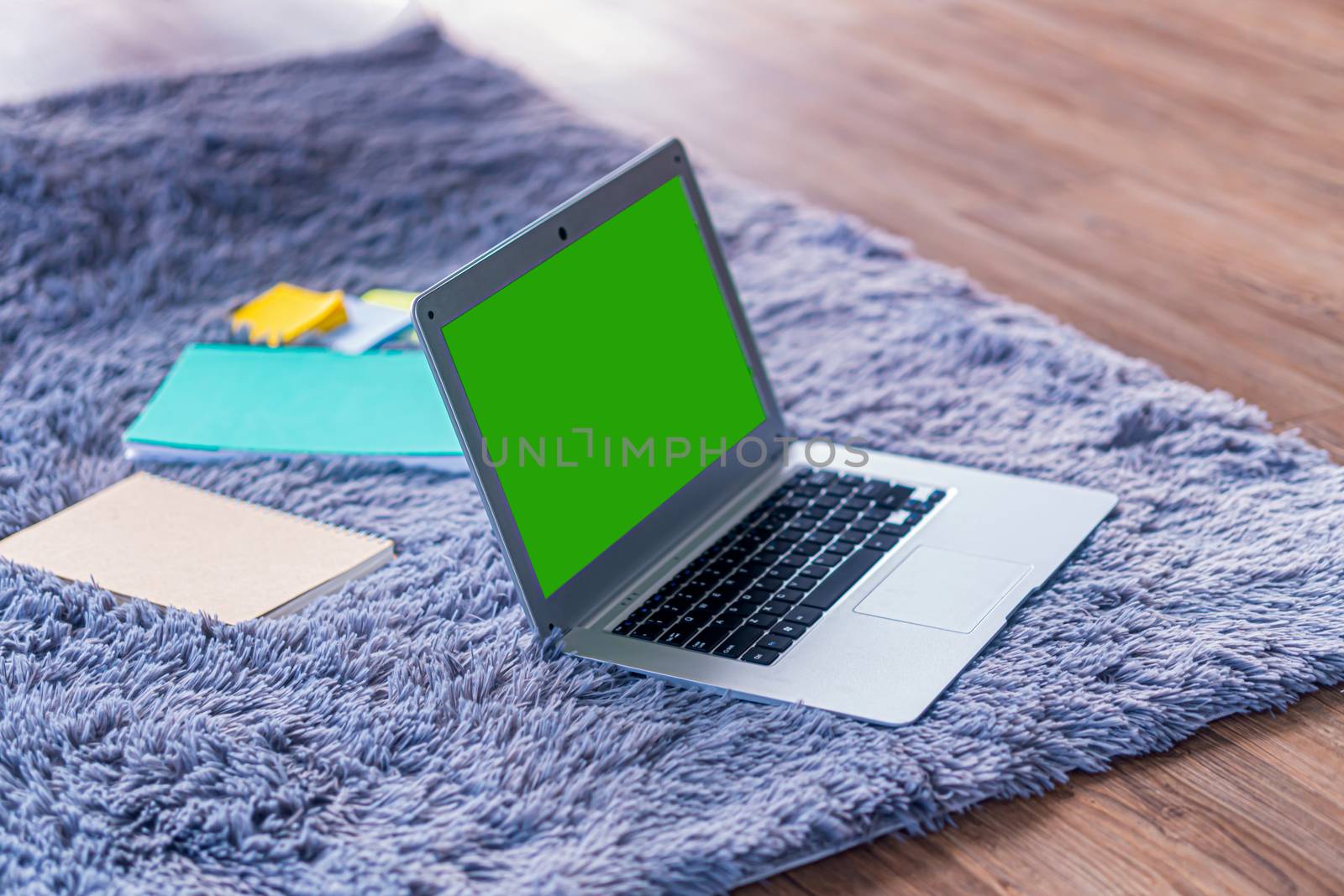 lap top computer with green screen on gray carpet