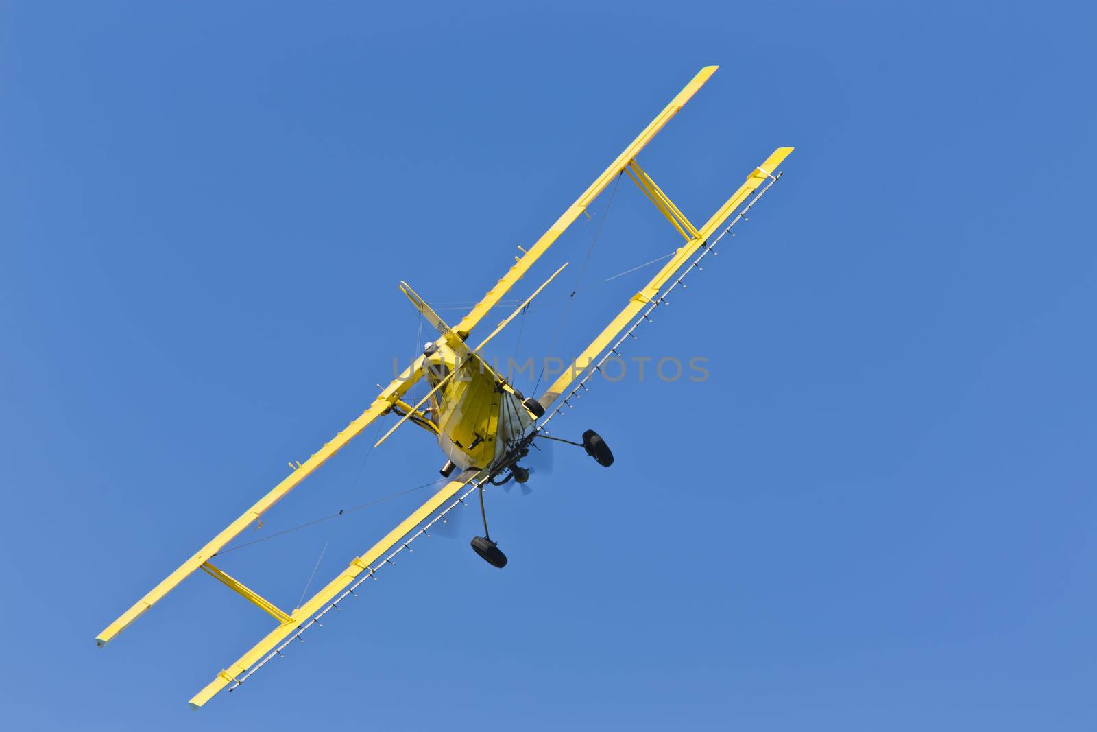 A crop duster applies chemicals to a field of vegetation.