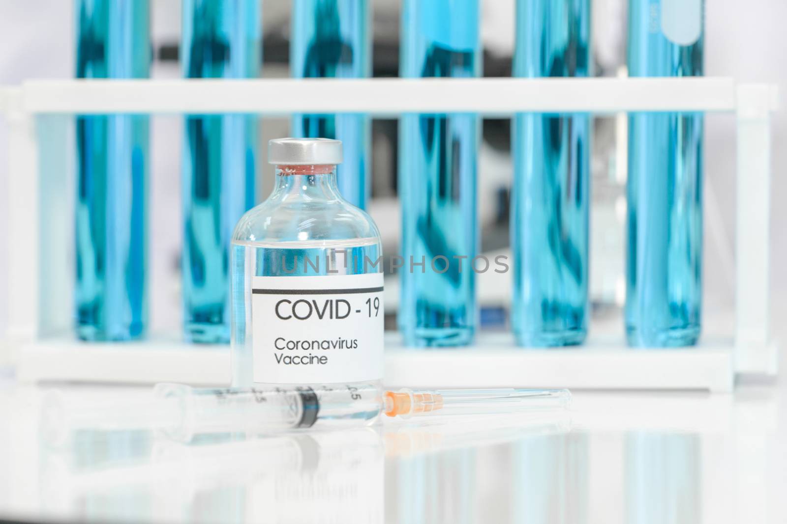 Bottle of coronavirus vaccine and syringe on white table. by chadchai_k