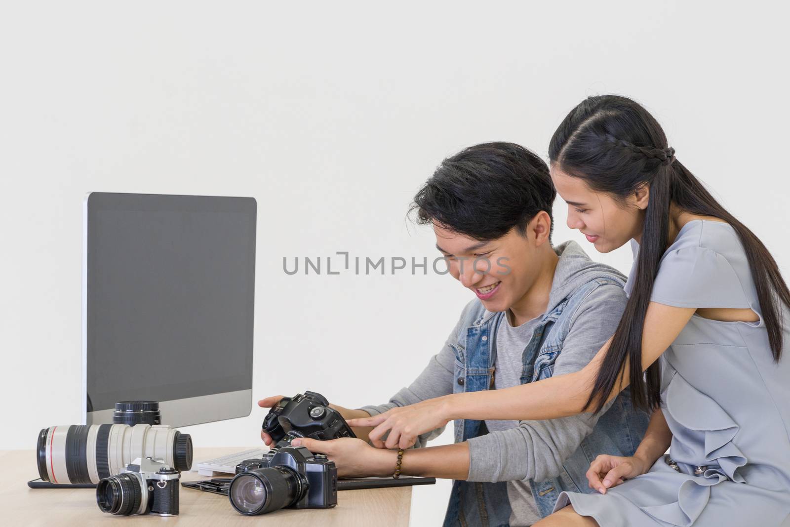 Asian photographer and model looking at pictures taken on the camera screen. The young model is very satisfied with her photo. The atmosphere in the photo studio.
