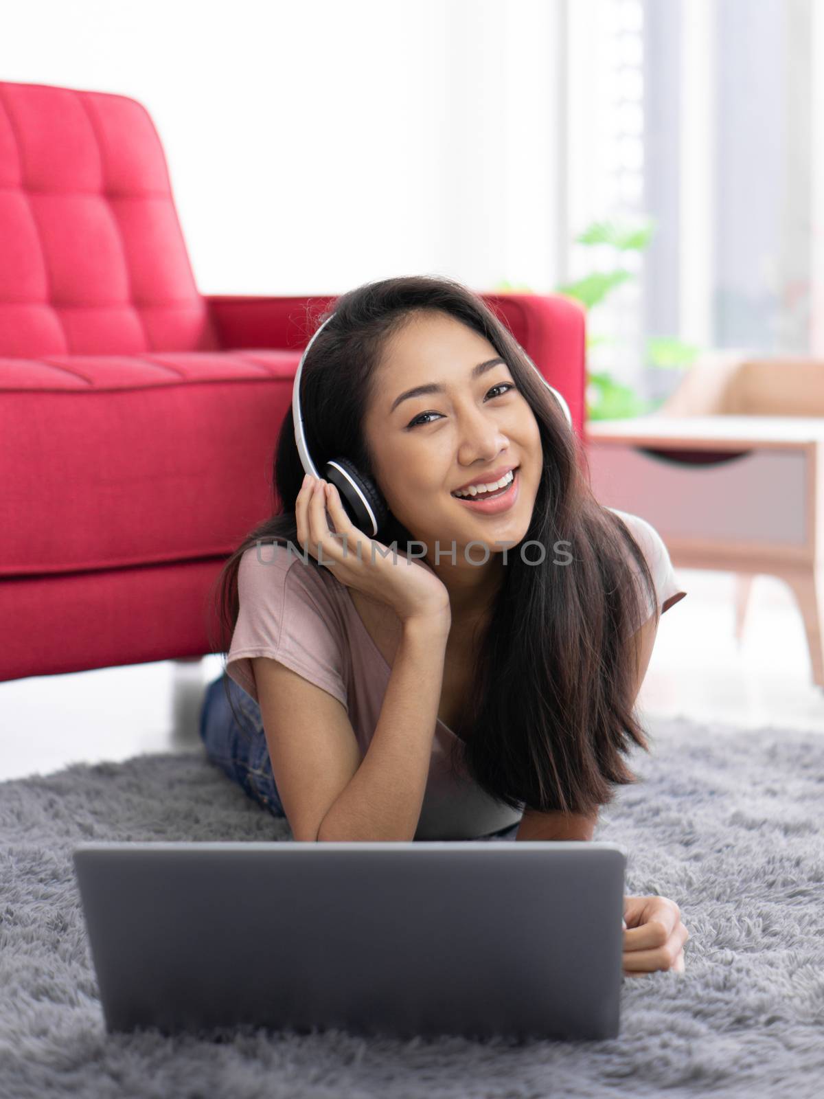 Teen wearing headphones listening to music relax in living room by chadchai_k