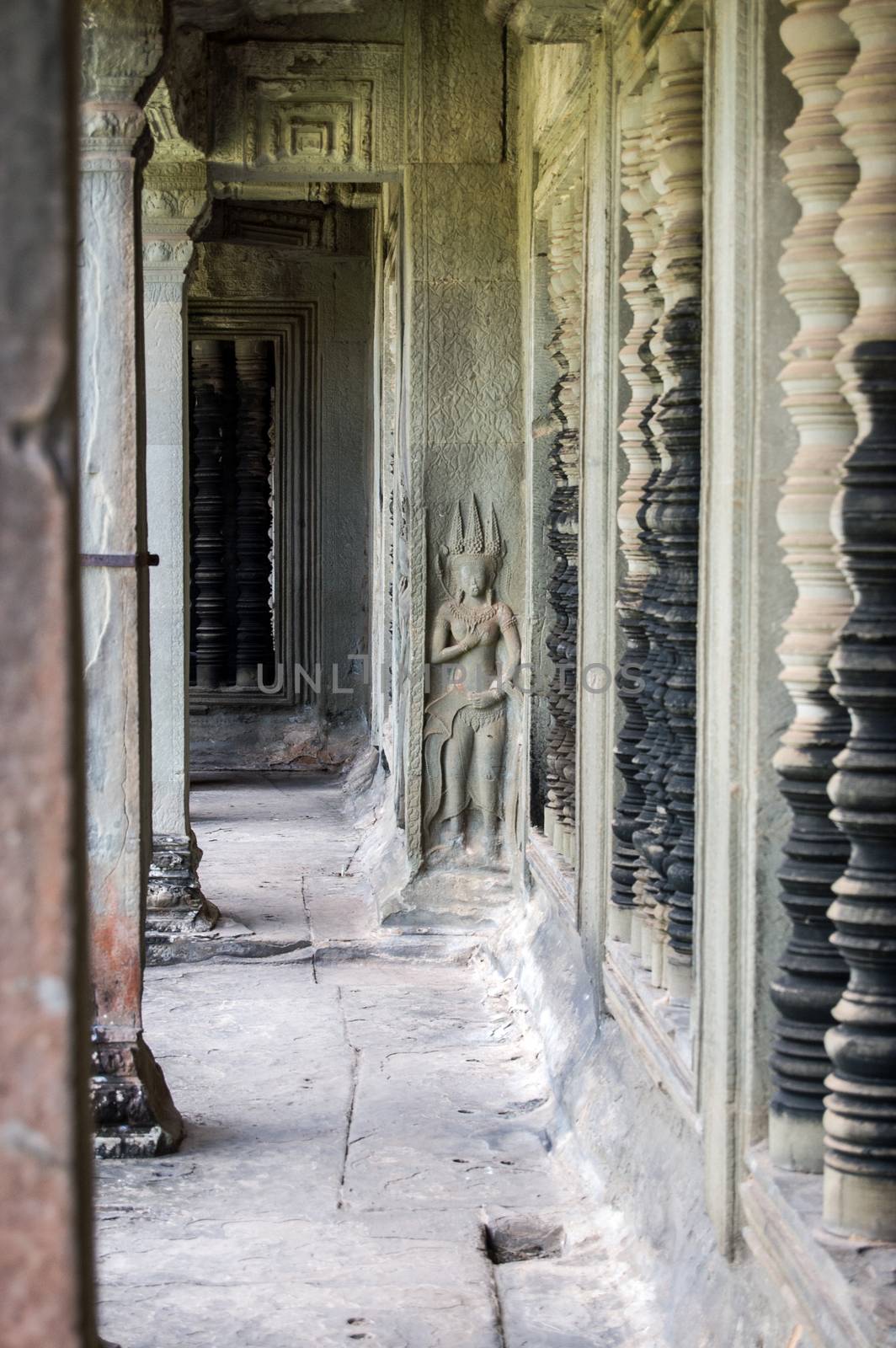 Interior of the Northern Gallery of the ancient Khmer Angkor Wat temple, Siem Reap, Cambodia. Turned stone window bars are on the right hand side, a carved Apsara dancer is in the centre.