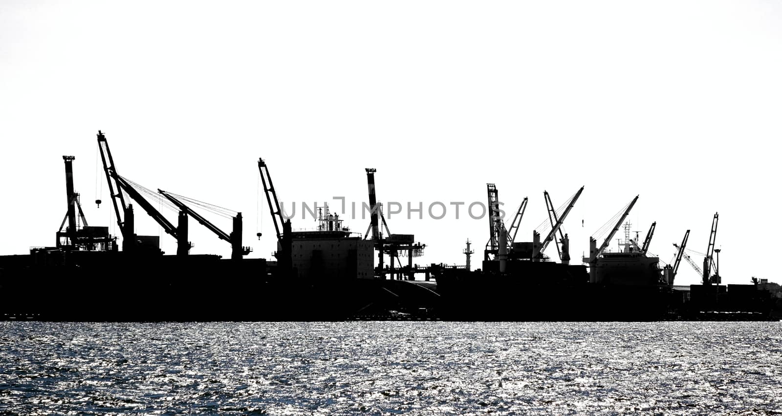 A row of loading cranes in Kaohsiung port seen in silhouette