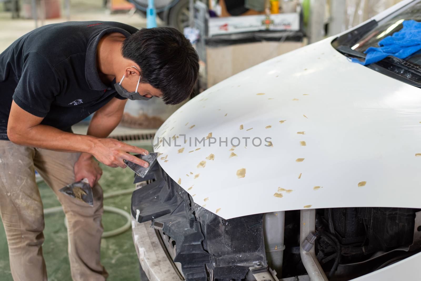 Bangkok, Thailand - August 31, 2017 : Unidentified denter or car mechanic serviceman check and fix body work and fiber bumper body part for fix and repair problem at car garage or repair shop