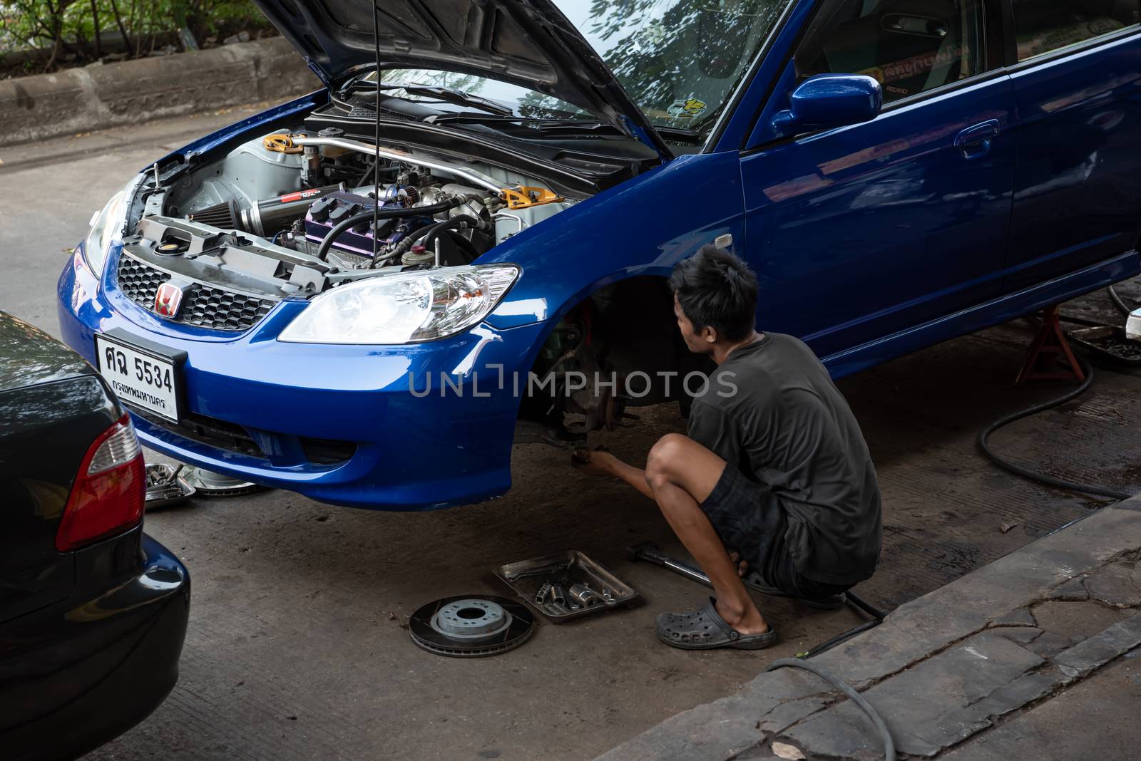 Bangkok, Thailand - February 1, 2020 : Unidentified car mechanic or serviceman disassembly and checking a disc brake and asbestos brake pads for fix and repair problem at car garage or repair shop