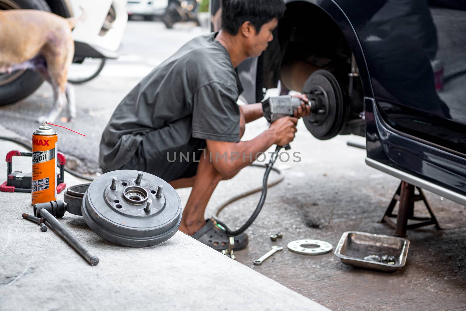 Bangkok, Thailand - February 15, 2020 : Unidentified car mechanic or serviceman disassembly and checking a disc brake and asbestos brake pads for fix and repair problem at car garage or repair shop