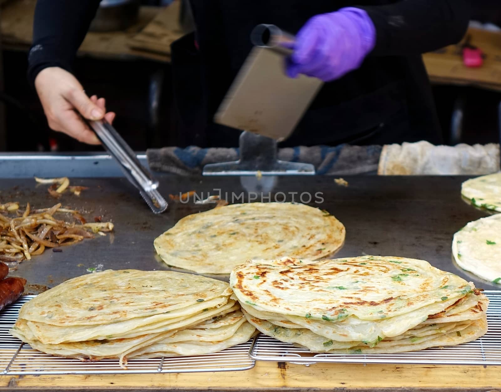A street food stall offers pancakes with spring onions cooked on a hot griddle