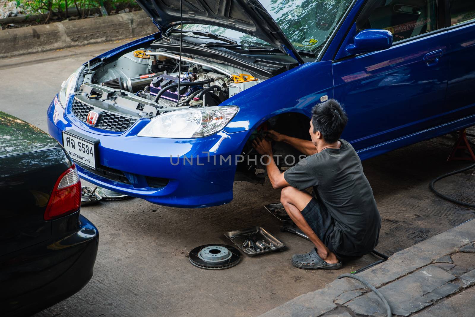 Bangkok, Thailand - February 1, 2020 : Unidentified car mechanic or serviceman disassembly and checking a disc brake and asbestos brake pads for fix and repair problem at car garage or repair shop