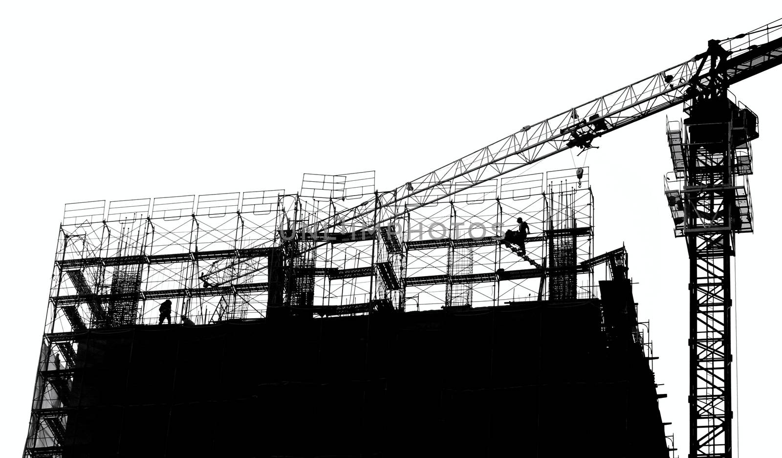 Construction site with crane and scaffolding seen as a silhouette