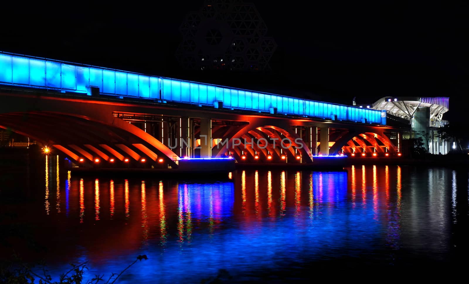 Evening view of the Love River with the illuminated light rail bridge and the True Love Pier station.