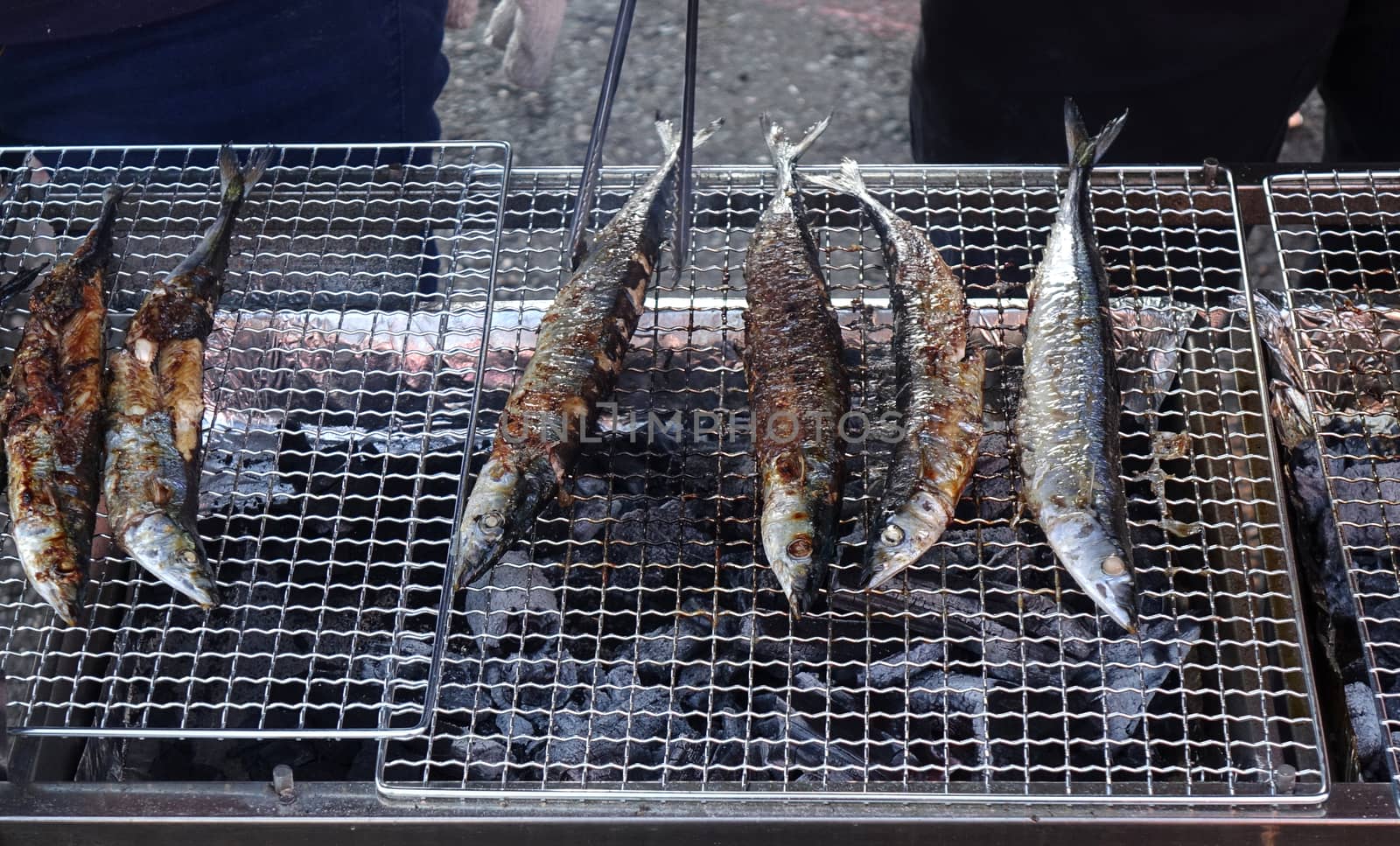 A street vendor cooks Pacific saury on a charcoal grill

