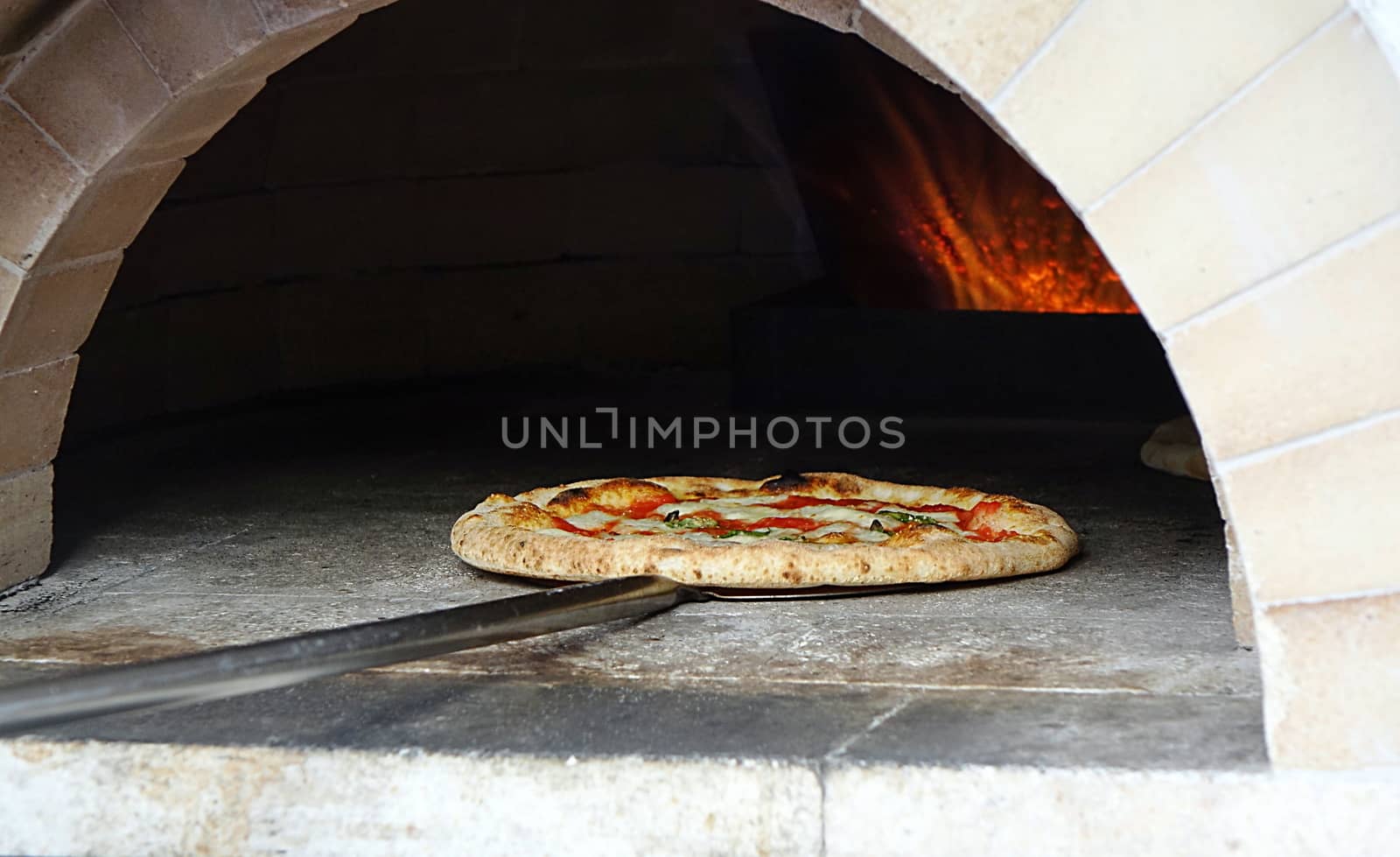 Pizza margherita with tomatoes, cheese and fresh basil is baking in the oven