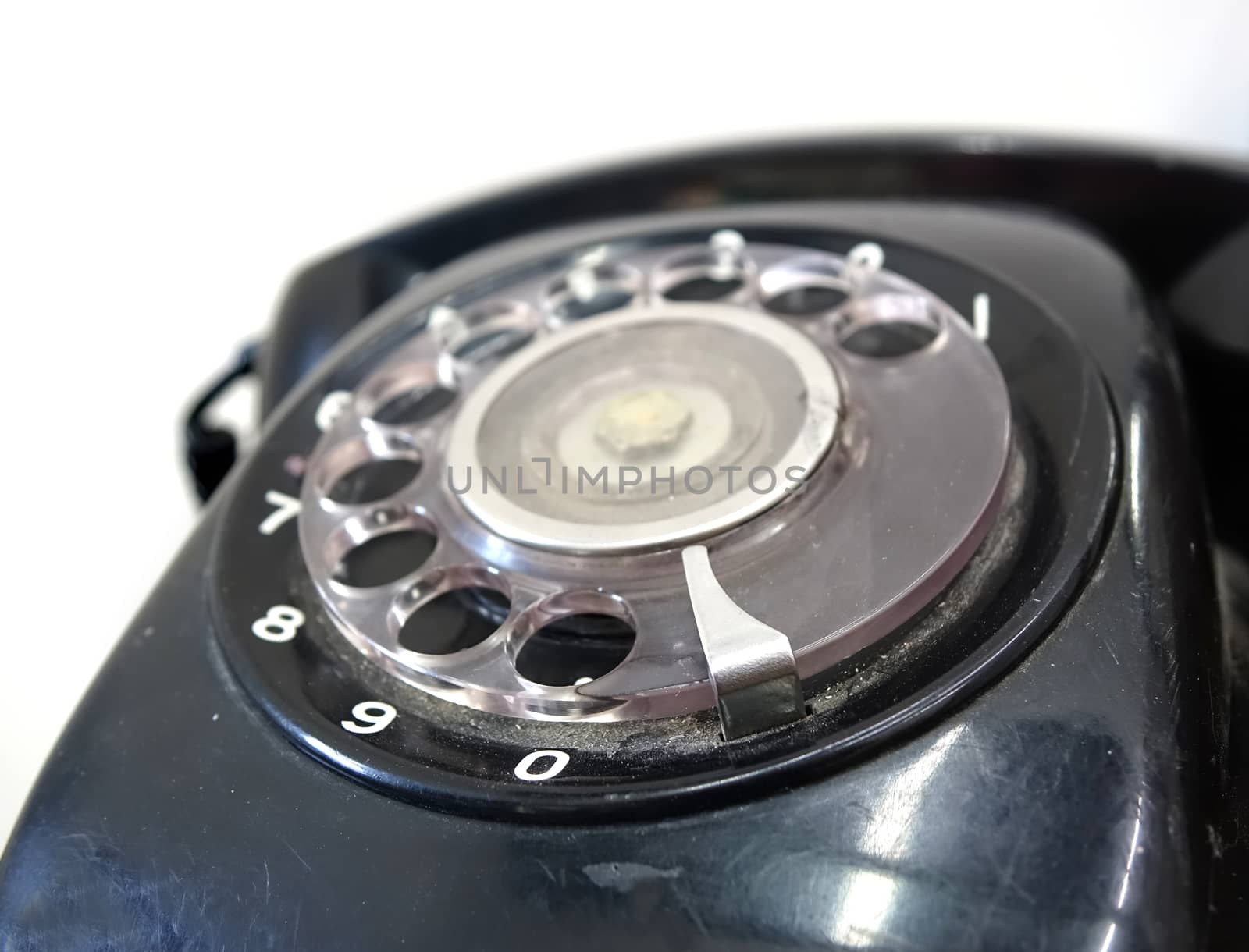 A black vintage rotary dial phone with a circular dialing wheel
