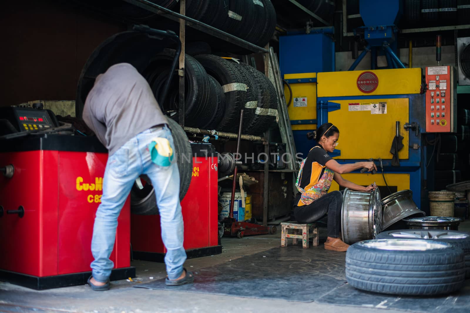 Bangkok, Thailand - September 1, 2017 : Unidentified car mechanic or serviceman disassembly and checking a car alloy chrome wheel for fix and repair suspension problem at car garage or repair shop