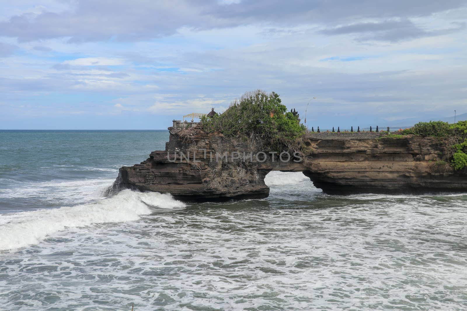 Batu Bolong beach which has an tourism attraction spot close to Tanah Lot temple. Huge hole in rock cliff below Pura Batu Bolong temple. Hindu Temple on the Beatiful Rock in the morning light, Bali.
