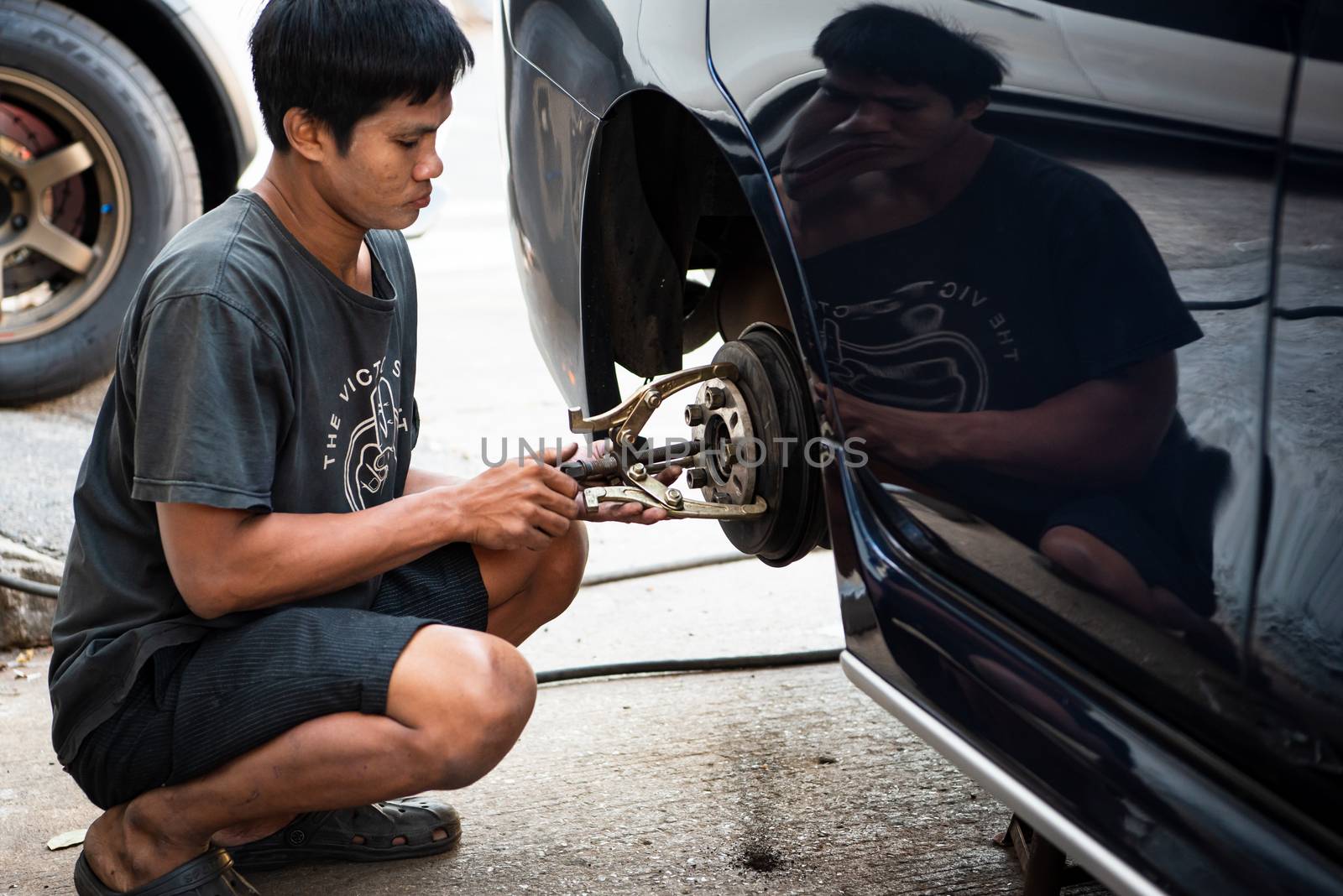 Bangkok, Thailand - February 15, 2020 : Unidentified car mechanic or serviceman disassembly and checking a disc brake and asbestos brake pads for fix and repair problem at car garage or repair shop