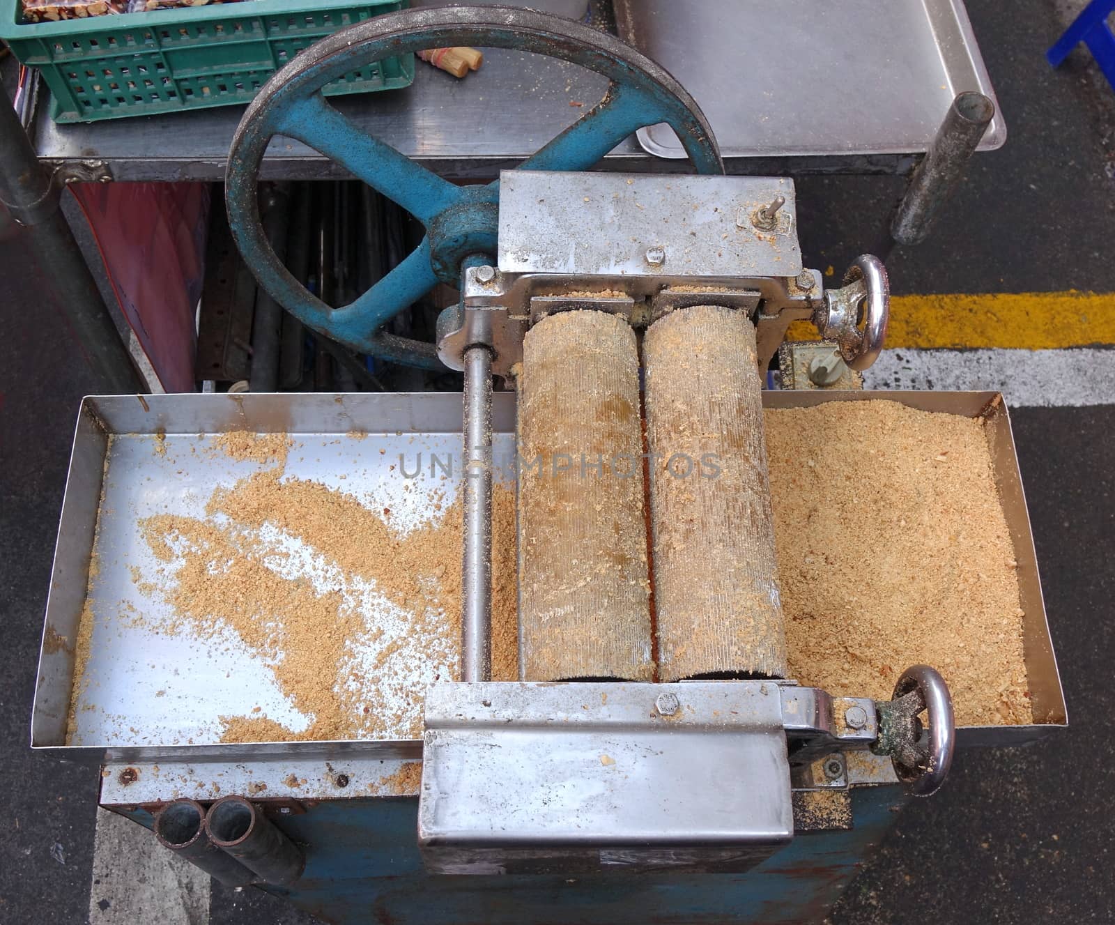 A market stall uses a hand-operated vintage peanut crusher to make peanut candy
