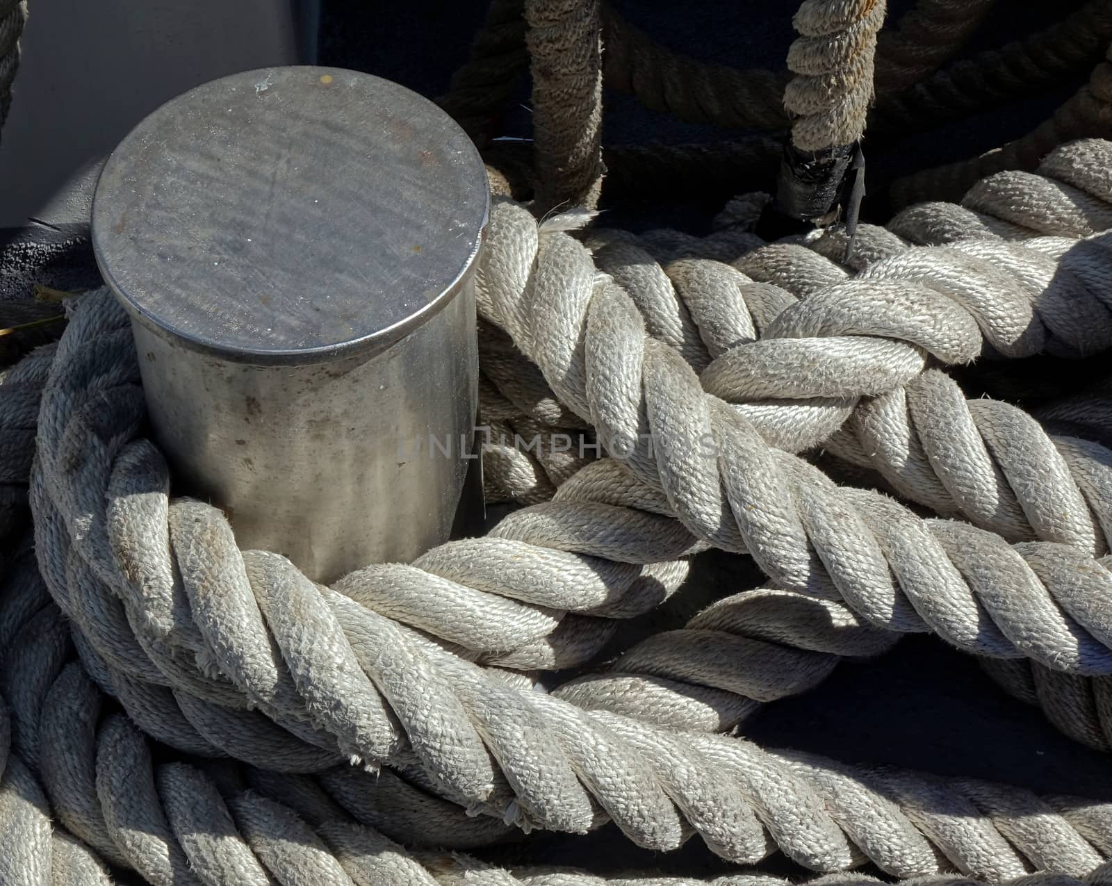 A steel mooring post with a thick rope wrapped around it
