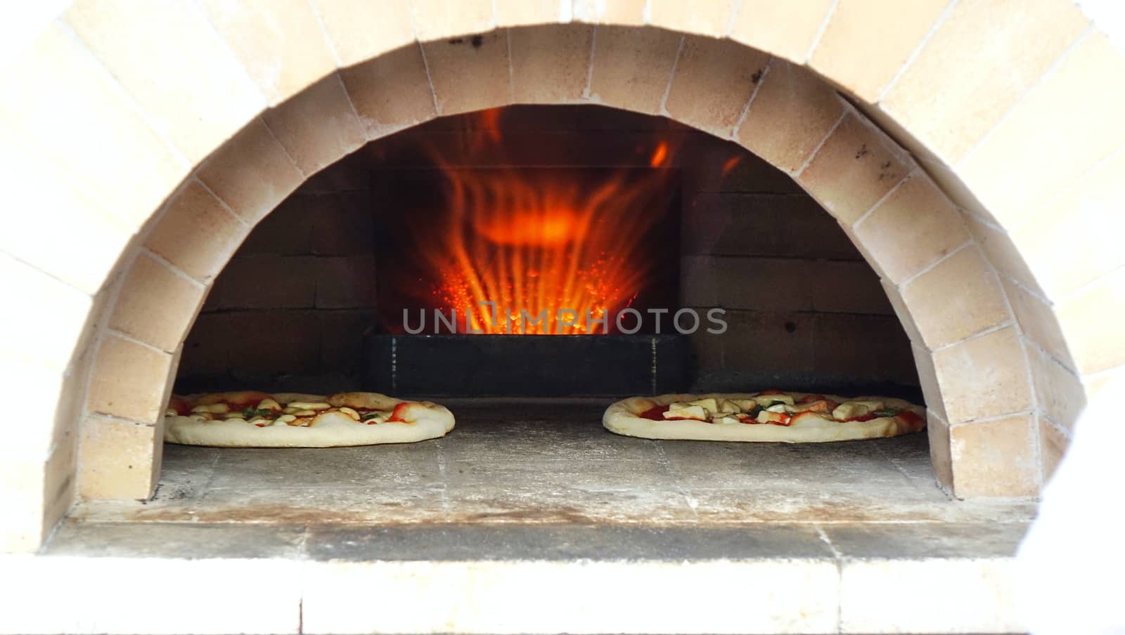 Pizza margherita with tomatoes, cheese and fresh basil is baking in the oven