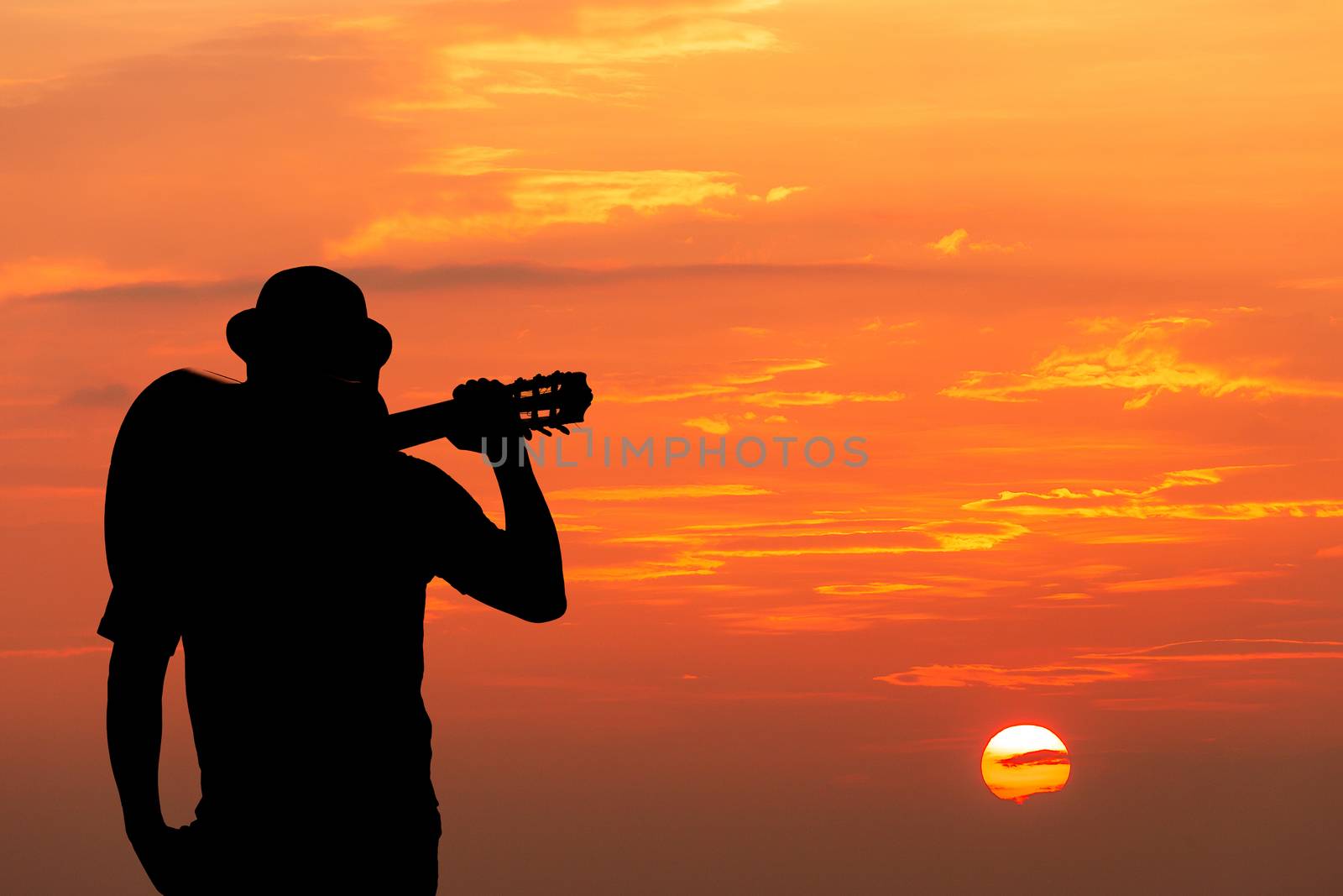 The young man walks along the railroad tracks in the light of the sunset.