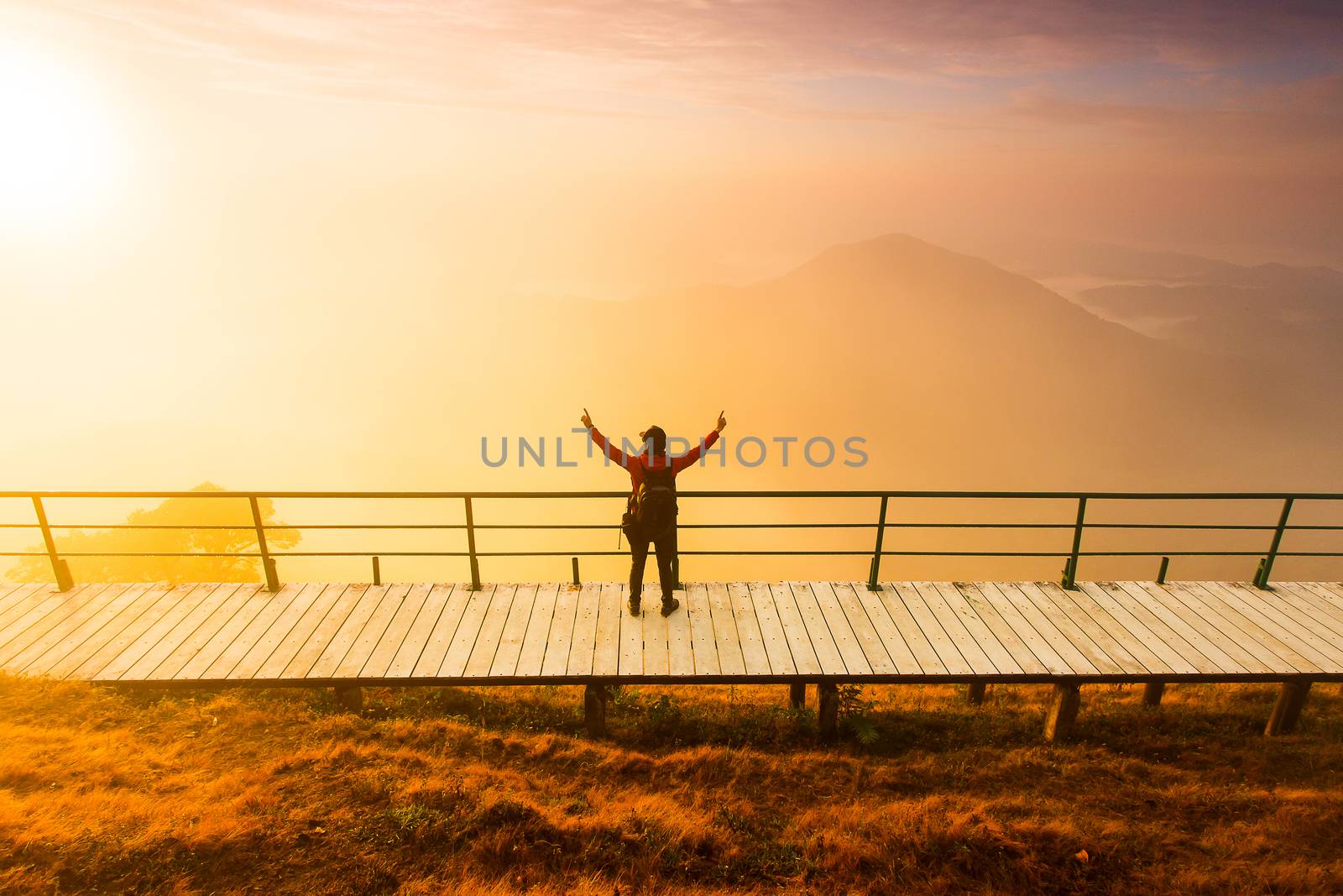 Silhouette of man hold up hands on the peak of mountain,success concept