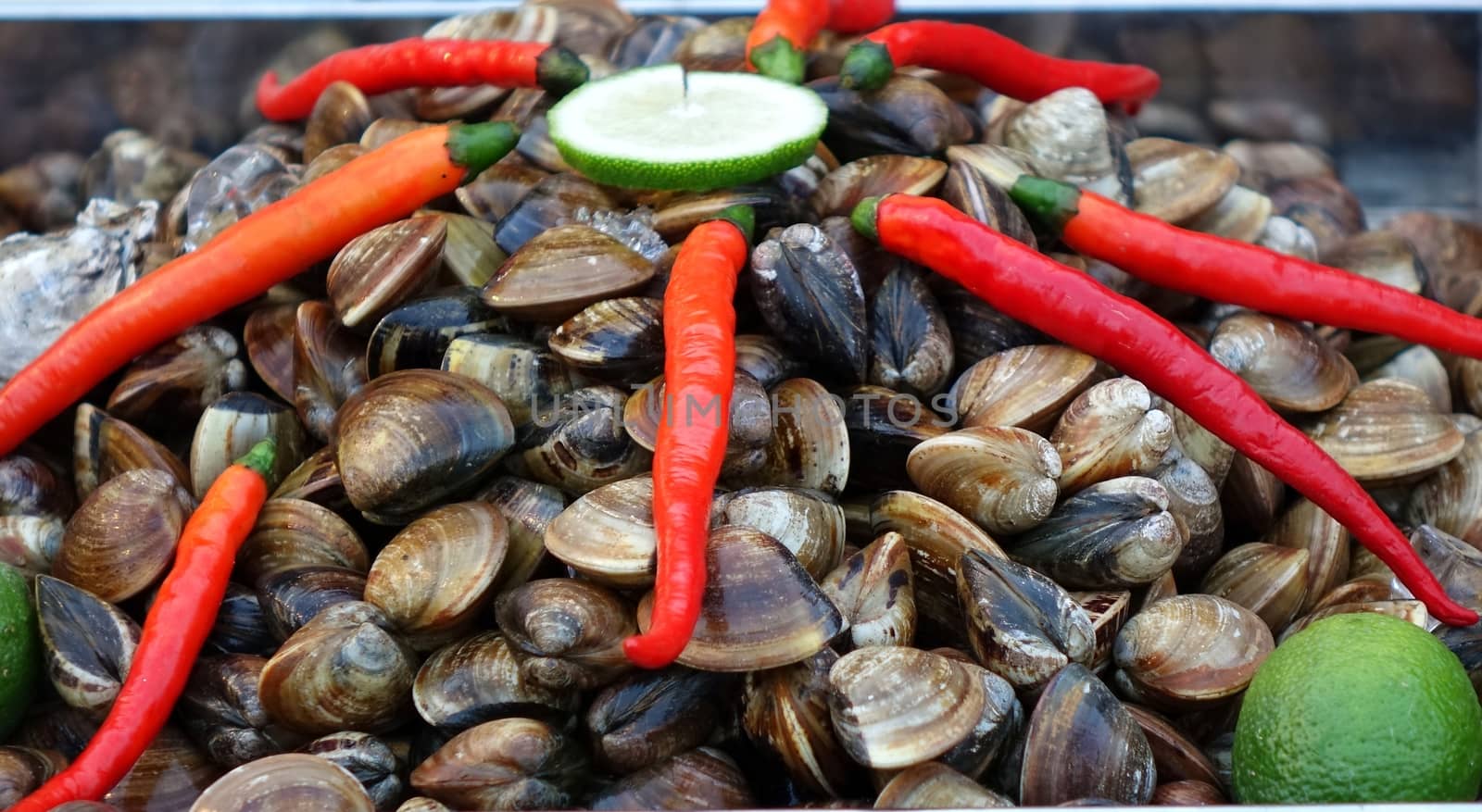 A street vendor sells fresh clams with chilies and lime slices