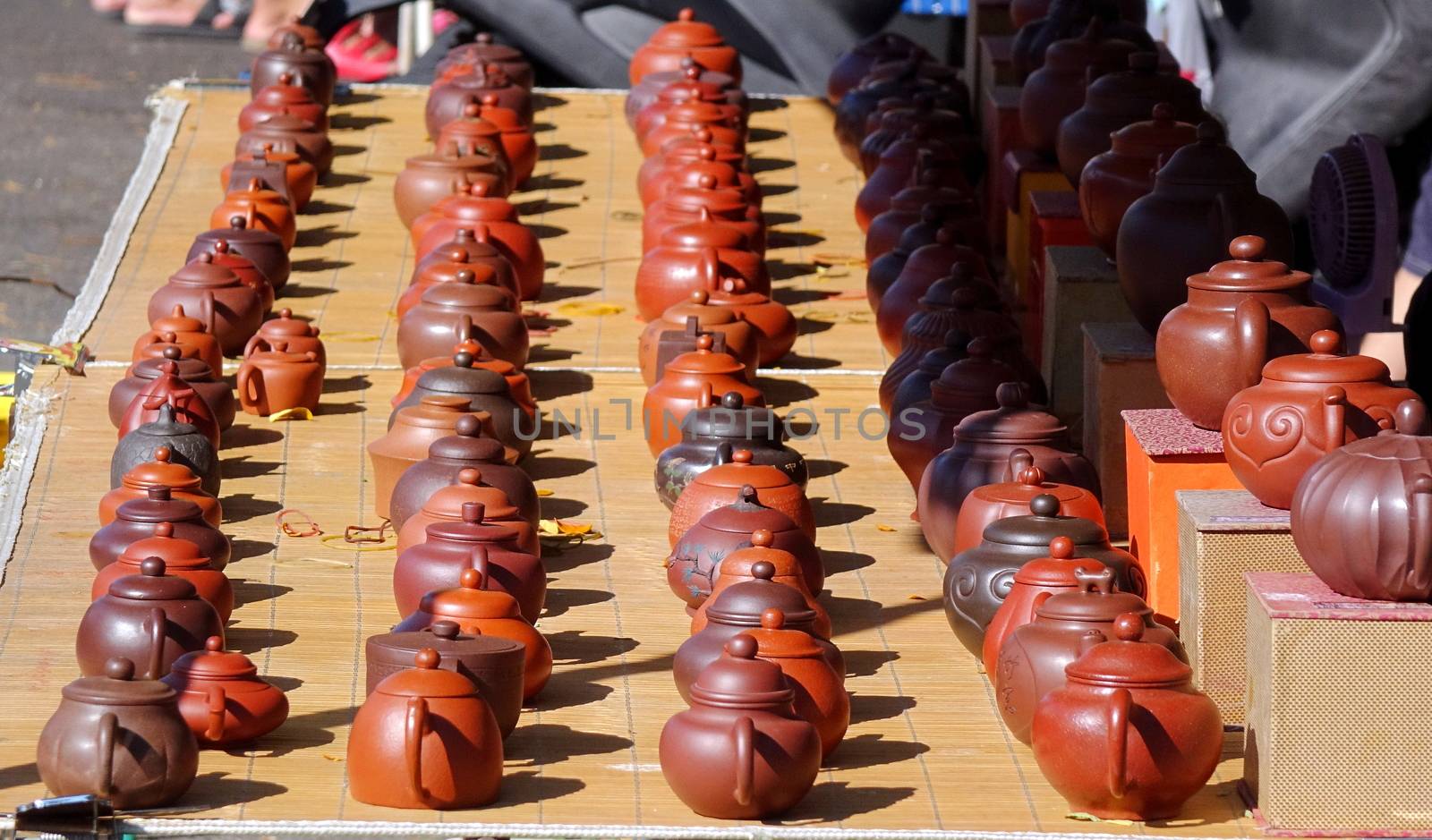 An outdoor vendor sells teapots made from characteristic red clay